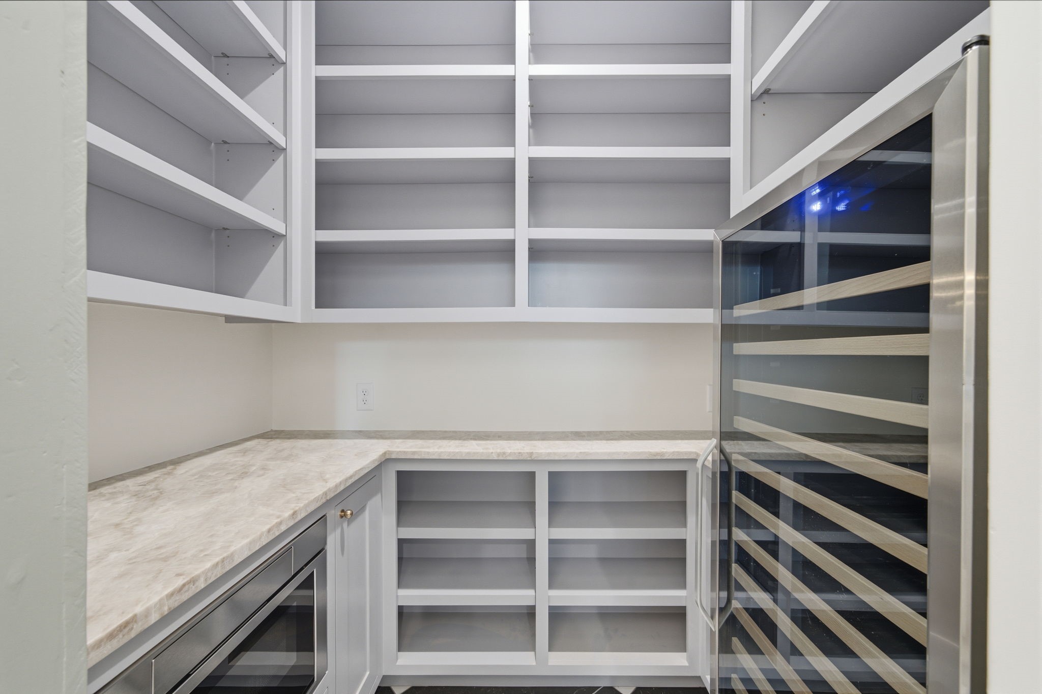 Microwave drawer and a wine fridge built into the pantry with ample shelving, perfect for organized storage and entertaining essentials.