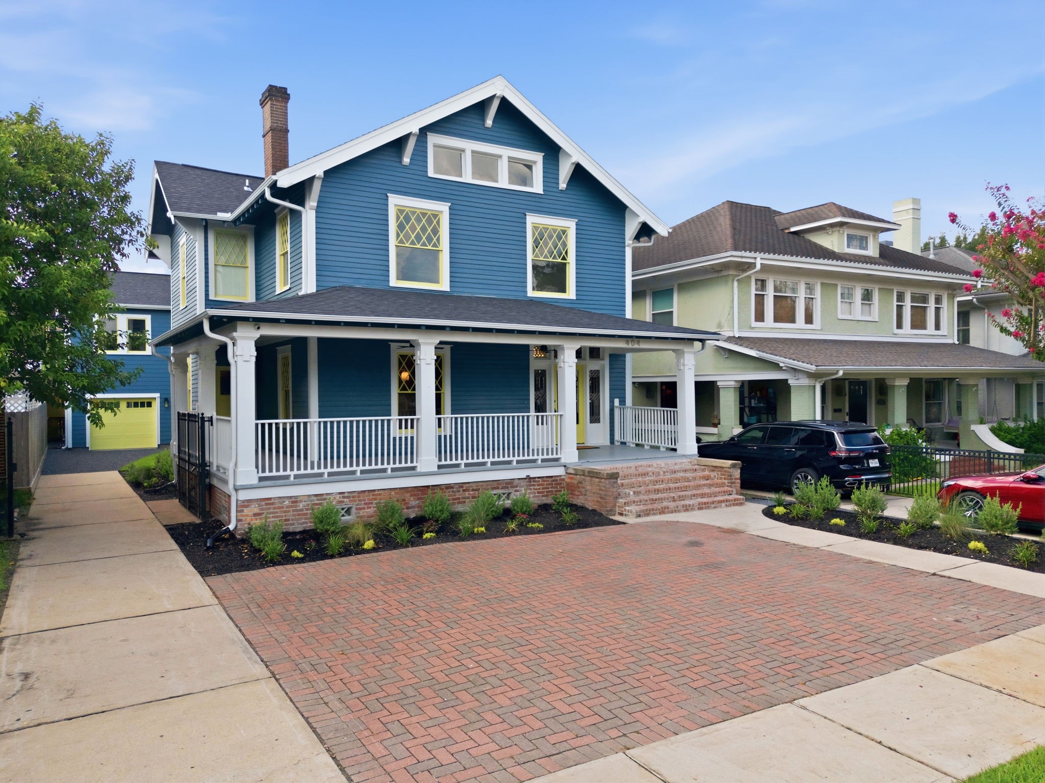 Charming two-story historic home with a welcoming front porch, elegant white trim, and a spacious bricked parking, perfect for family living.