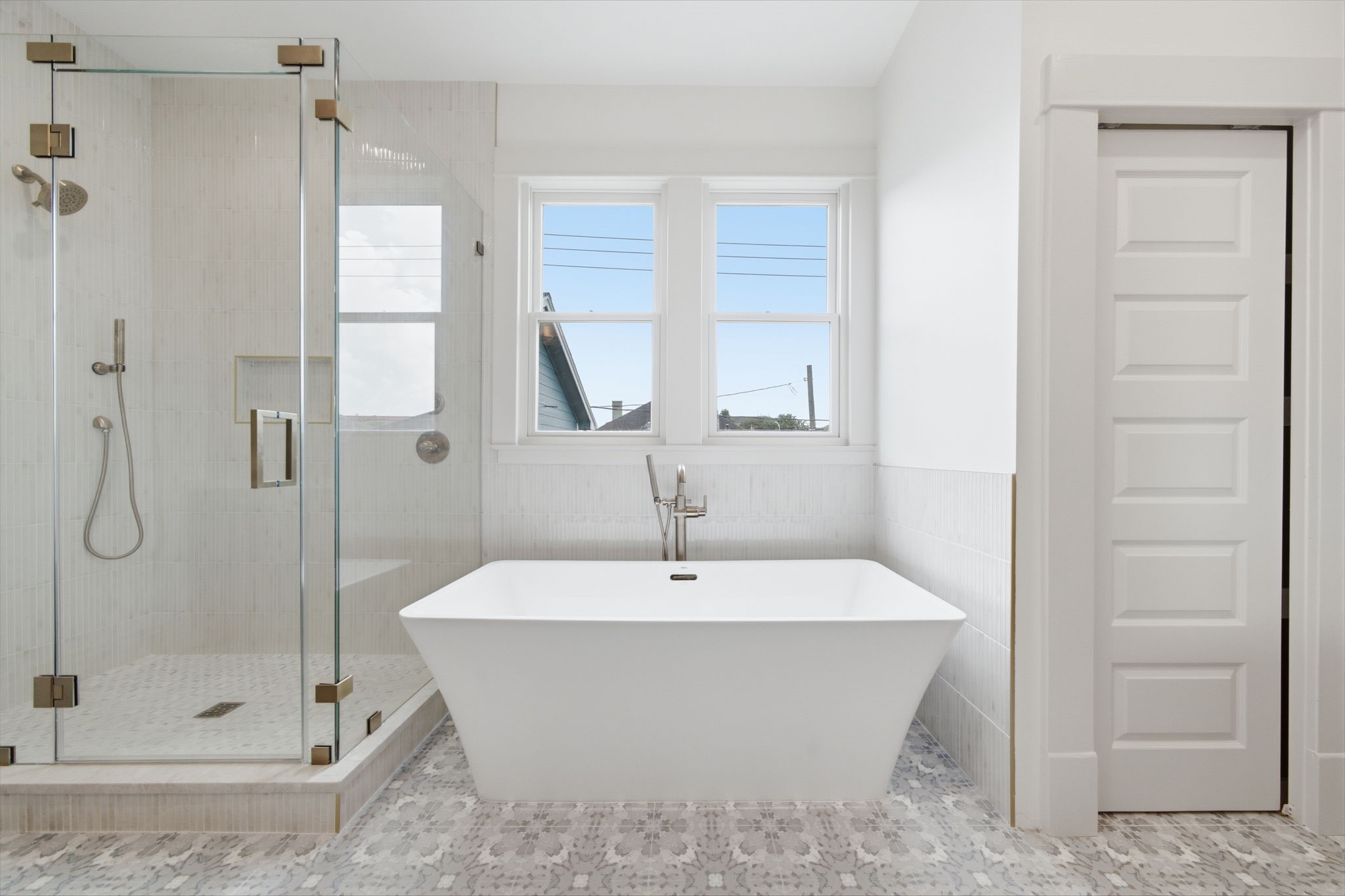 The primary bathroom featuring a spacious glass-enclosed shower and a luxurious 67 inch freestanding bathtub, accented by natural light.