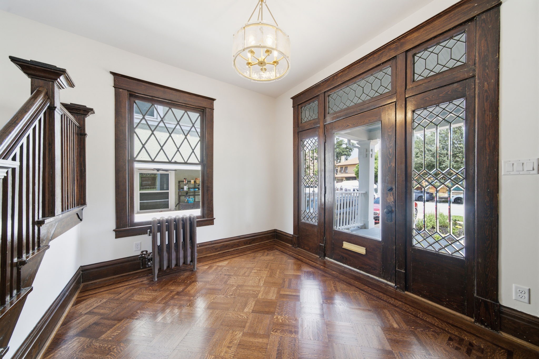 Entryway featuring rich woodwork, elegant leaded glass windows, and a classic chandelier, offering a warm welcome with its timeless character and natural light.