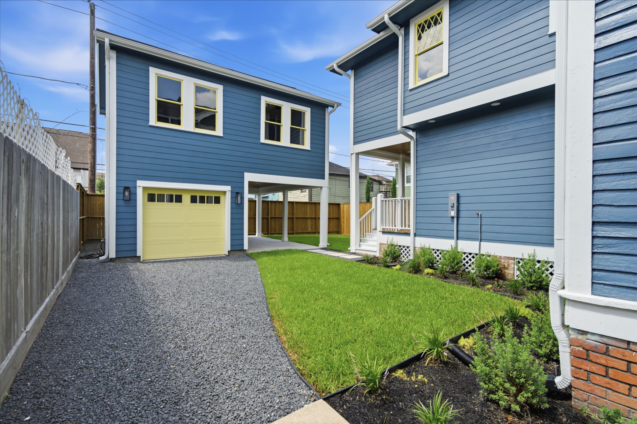 Neatly landscaped yard, featuring a gravel driveway leading to and detached garage and multiple porches.