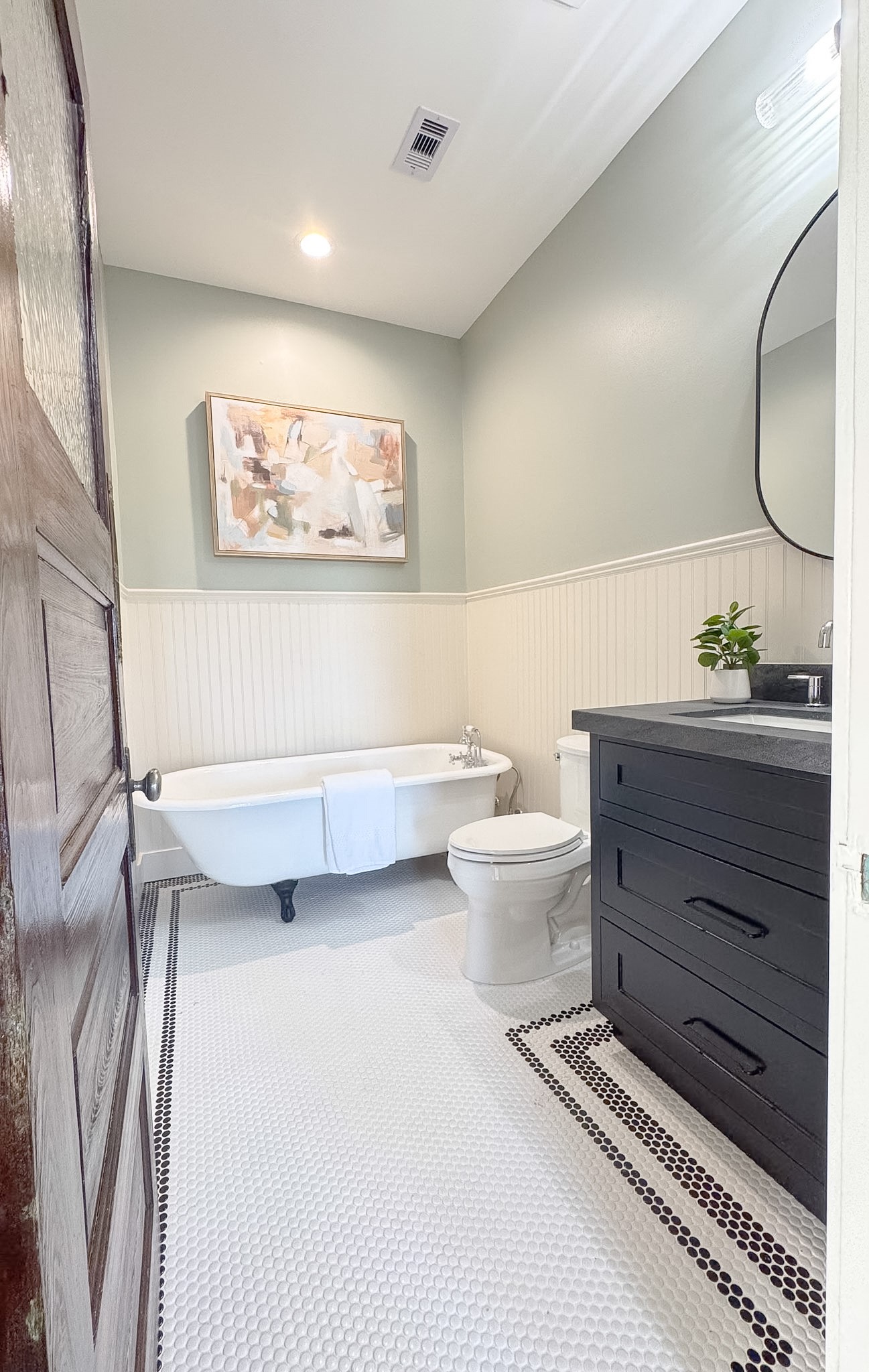 The original upstairs bathroom includes the original clawfoot tub, single vanity with sleek fixtures, and tasteful wainscoting for a timeless touch.