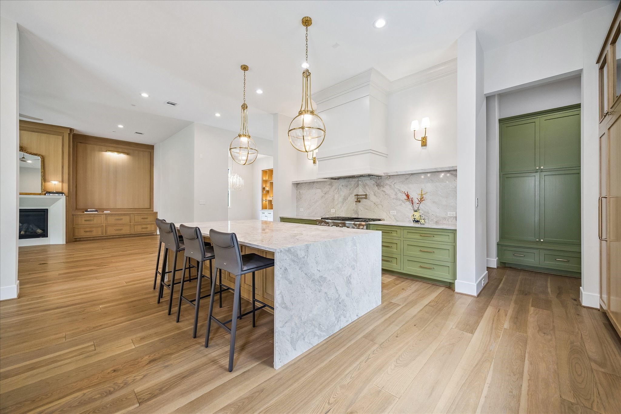 This well-equipped kitchen is designed for both functionality and style, complete with a pot filler, custom vent hood, and elegant brass accents.
The cabinetry is a beautiful blend of white oak and painted finishes, enhanced with brass accents and soft-close hardware for a seamless look. A hidden walk-in pantry offers extensive storage, ensuring that everything is kept neatly organized and easily accessible. This thoughtful design provides both convenience and an uncluttered aesthetic.