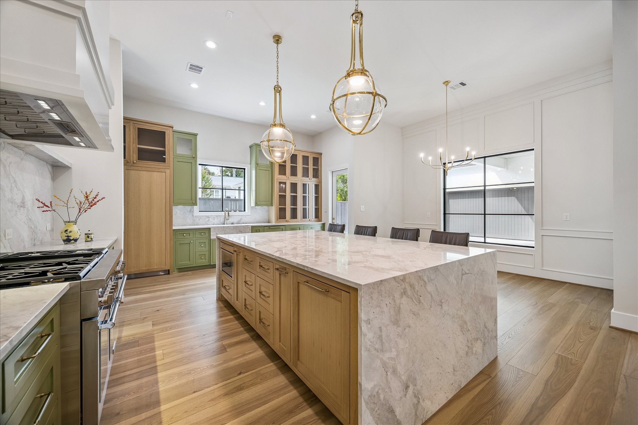 Complementing the kitchen is a cozy breakfast nook, an inviting space for enjoying meals with a view of the kitchen's designer pendants gracefully suspended over the island. This area perfectly combines practicality with a touch of elegance, making it a focal point for daily living and social gatherings.