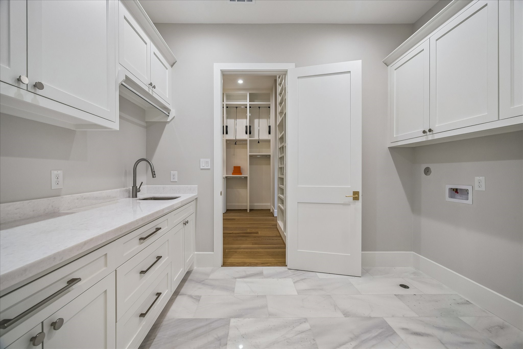 Ideally situated on the upper level, this thoughtfully designed laundry suite offers the ultimate in daily convenience with dual-access doors from both the main hallway and the primary bedroom. Designed to streamline your routine, the space features premium quartz countertops for effortless folding, high-end cabinetry, and a deep built-in utility sink.
