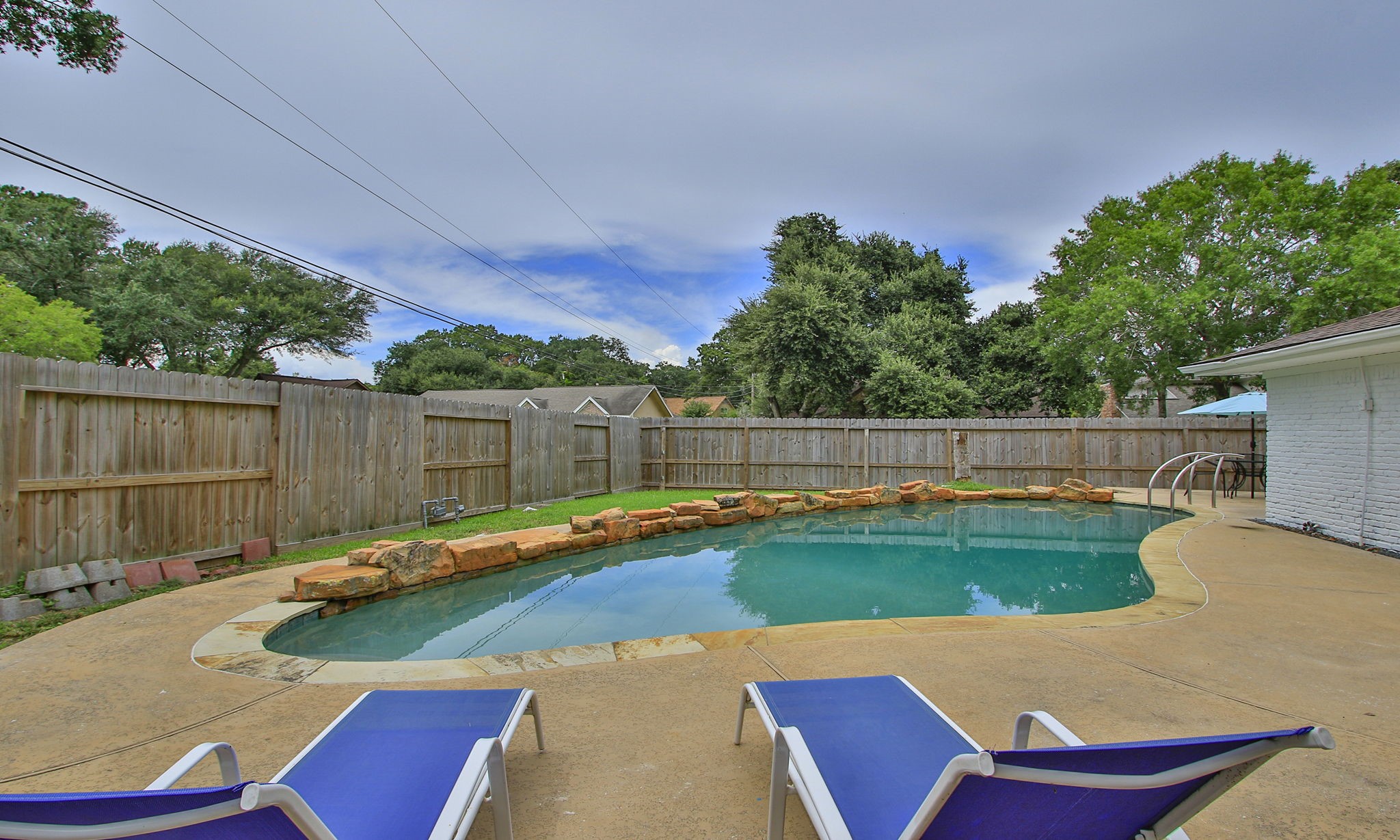 The charming, ample backyard, with a curved pool and covered porch is a focal point for entertainment.