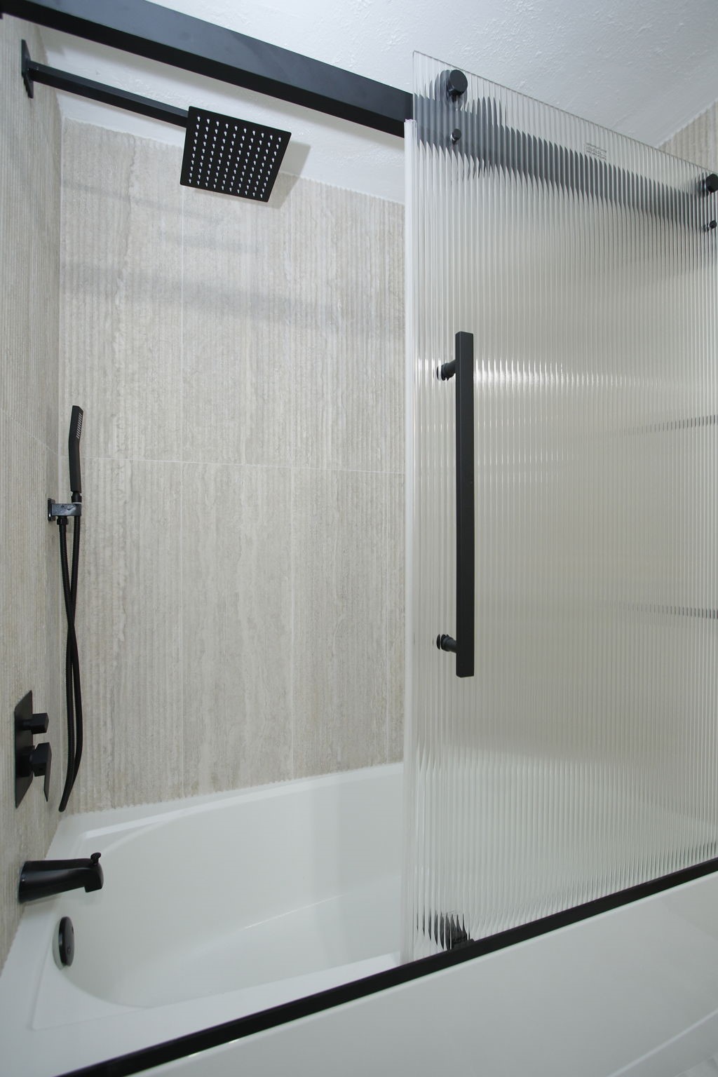 Main bathroom's shower / tub combo, with wooden like walls, rainfall showerhead and contrastind fixtures.