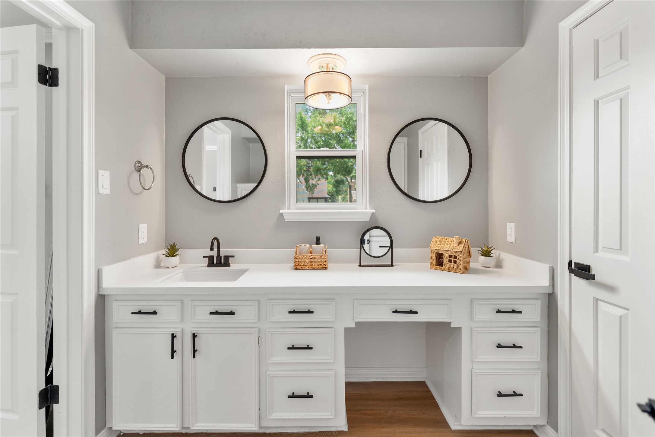 The bright, modern bathroom with quartz countertops, and sleek, contrasting fixtures, boasts ample storage space.