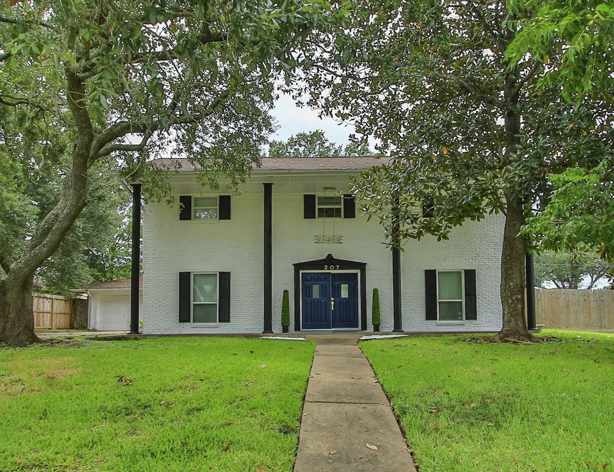 Majestic two-story home with a renovated facade, located in an oversized corner lot, framed by mature trees
