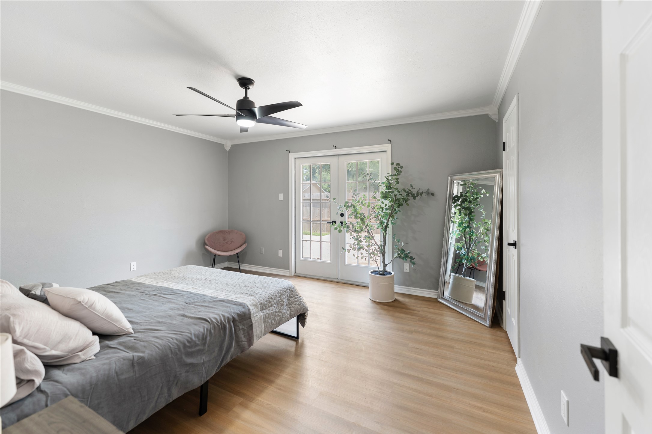 The spacious main bedroom features a modern ceiling fan, soft color palette, and hardwood floors. The elegant french door bring lots of sunshine making this an inviting room