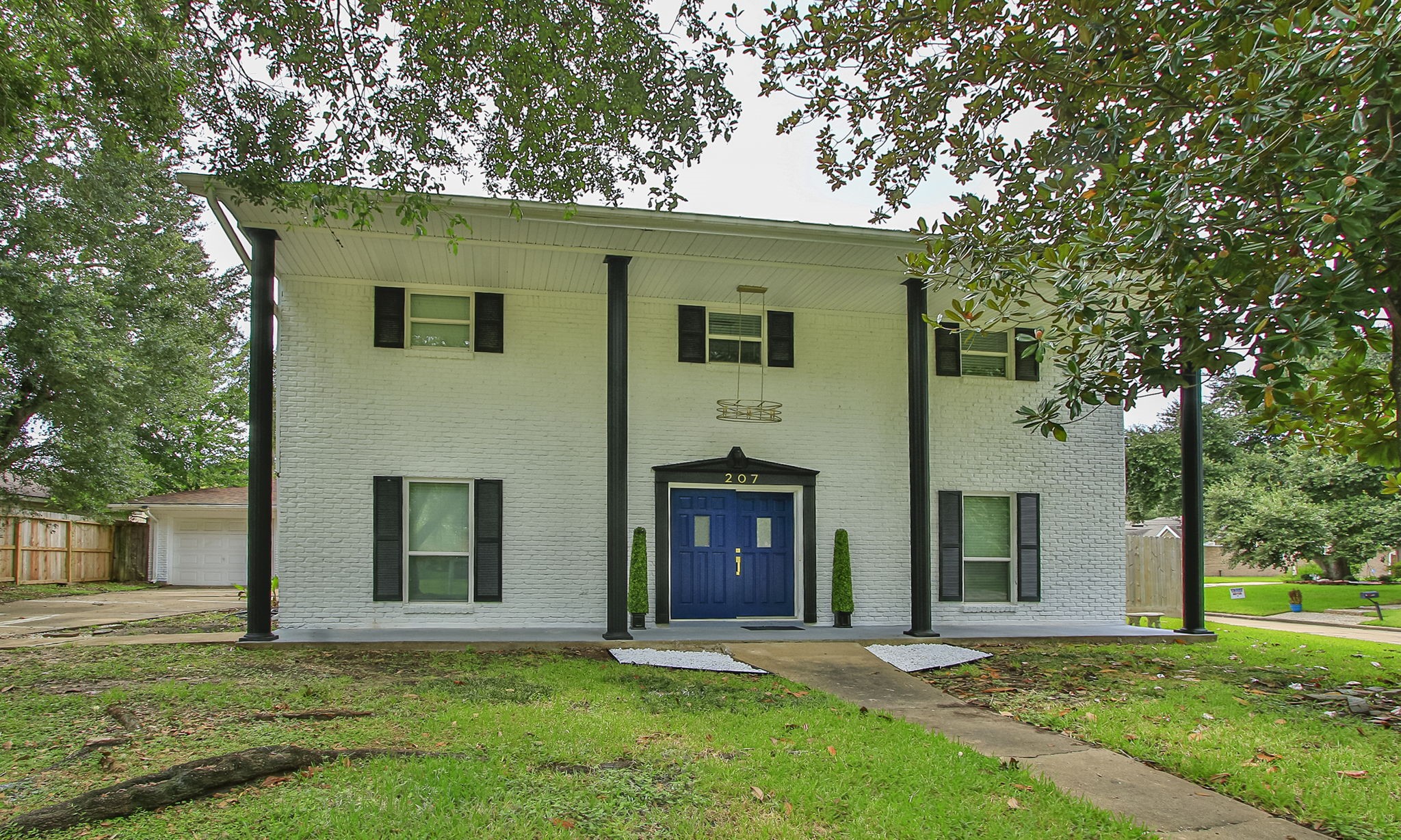 The bright facade, with contrasting colums and shutters and an elegant golden light fixture