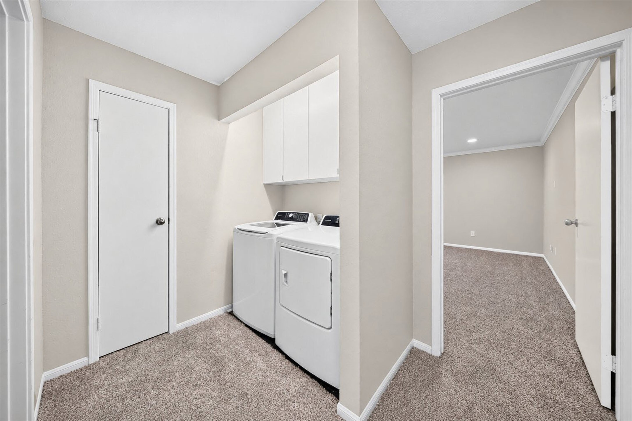 Laundry lives upstairs in its own nook with a full-size washer and dryer and cabinets above for supplies, just outside the second bedroom.