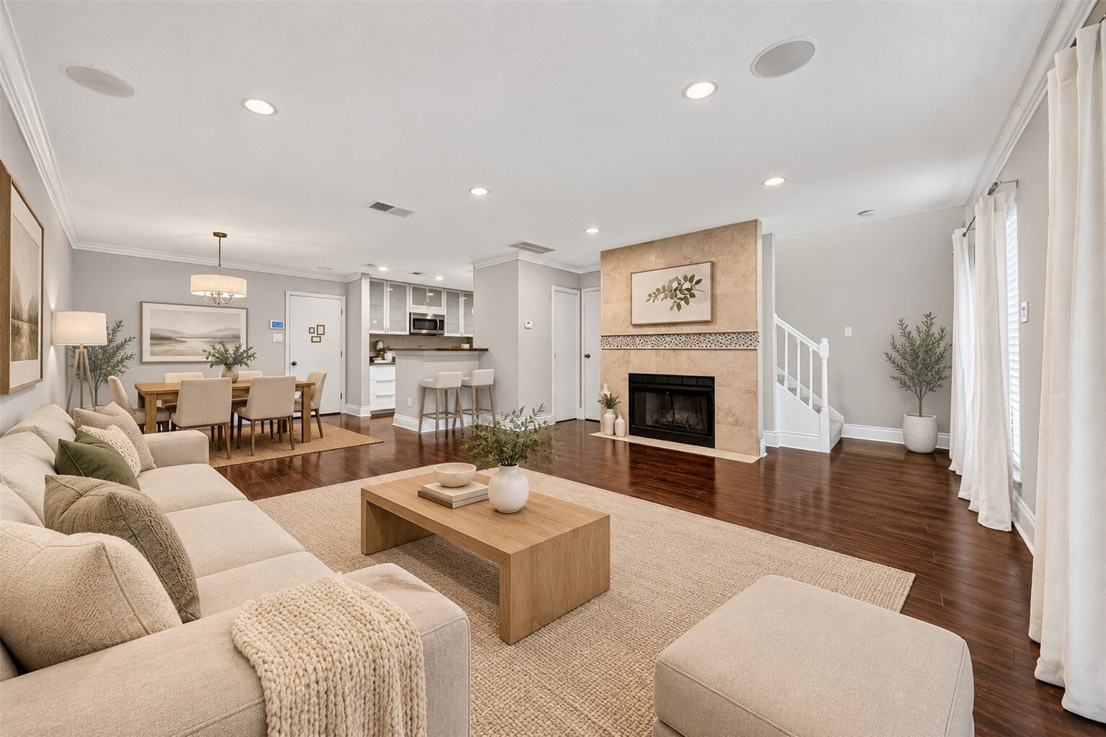 Virtually staged, the open living and dining space shows off gleaming dark hardwoods, a tiled fireplace surround, and room for a full dining set under the drum chandelier. The kitchen's breakfast bar connects it all.