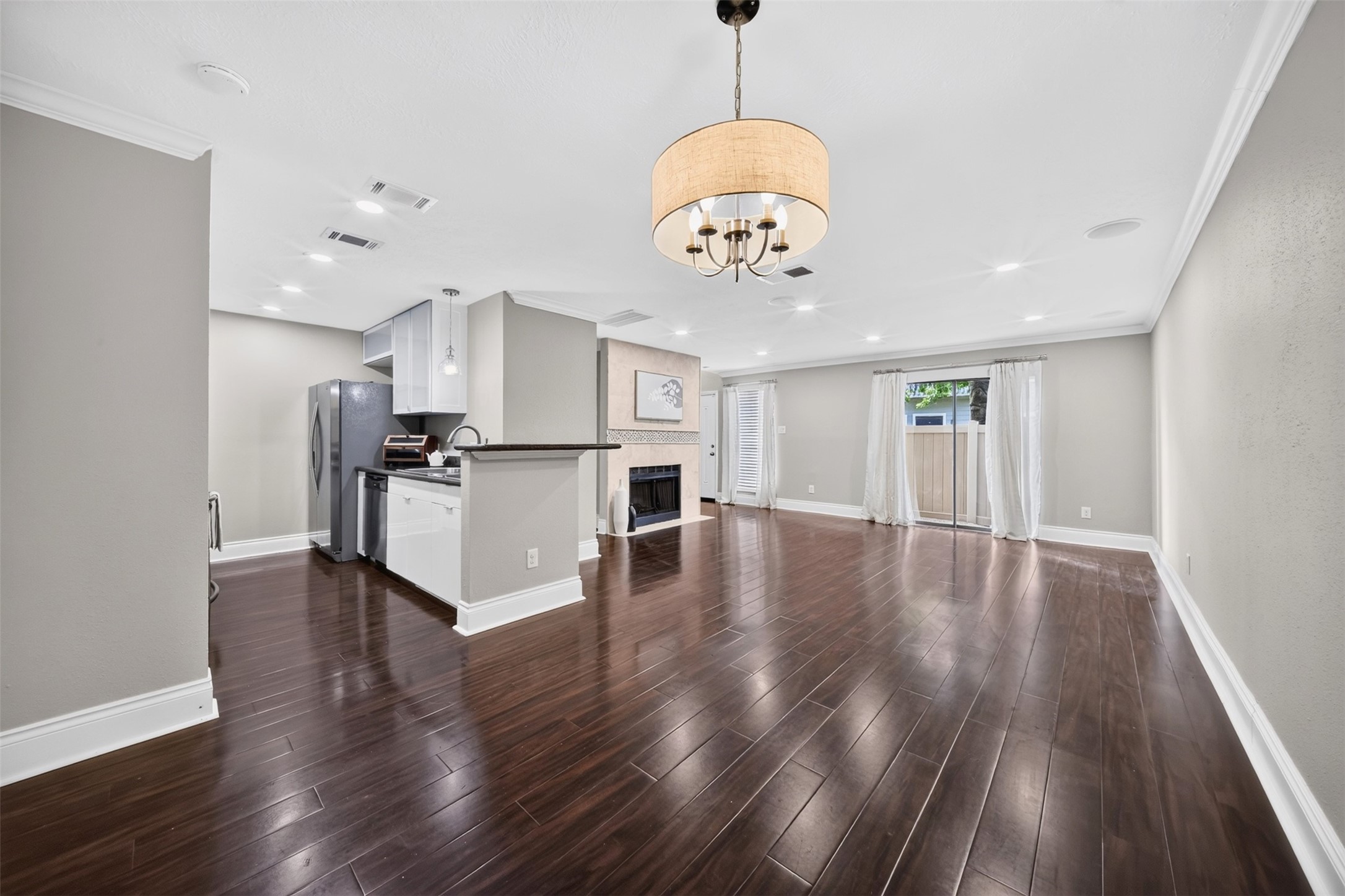 The dining nook pairs dark wood floors and crown molding with a fabric drum chandelier  sized for a full table with room to spare.