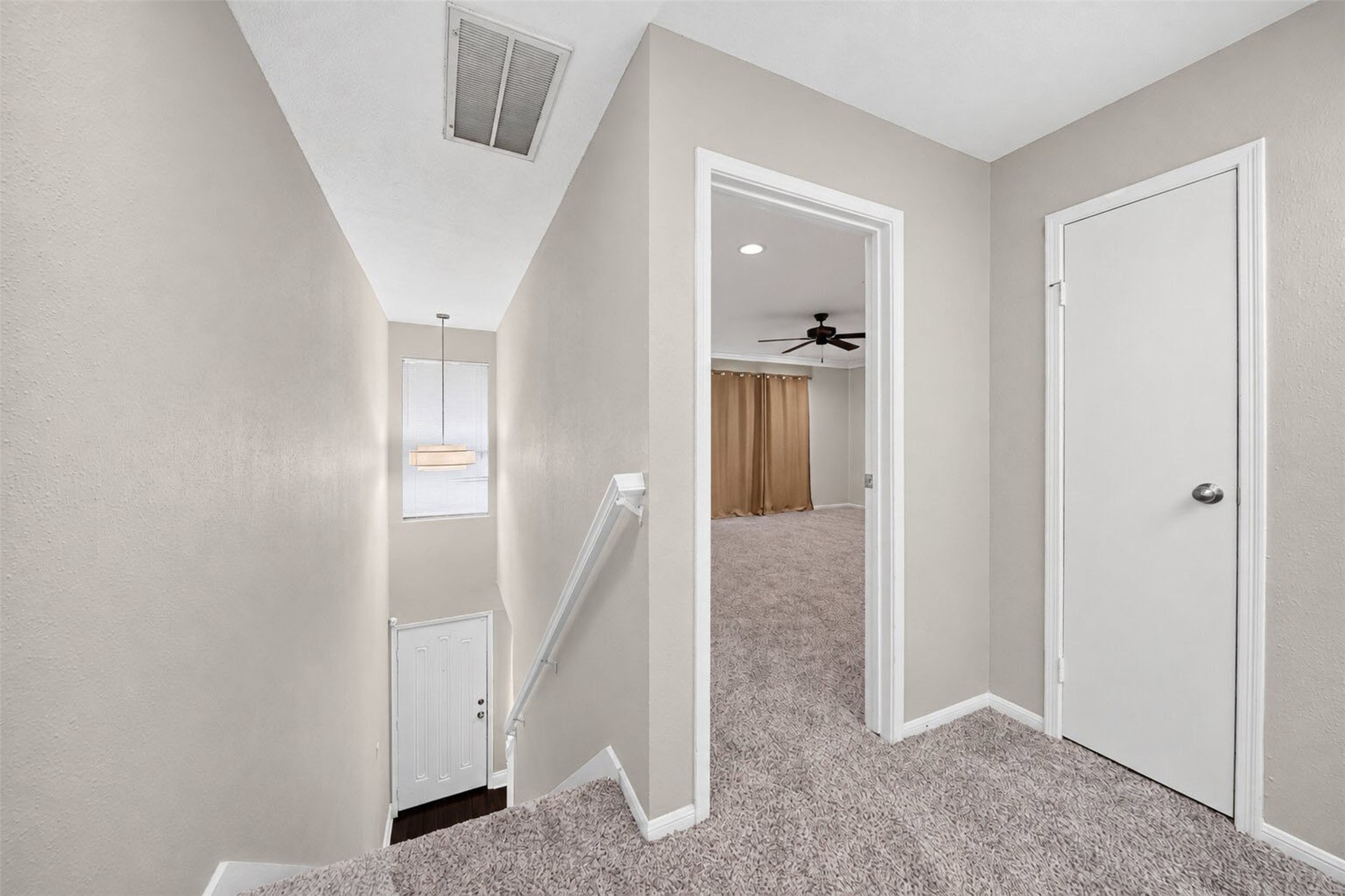 The carpeted upstairs landing overlooks the entry stairwell and front door below, and opens into the primary bedroom.