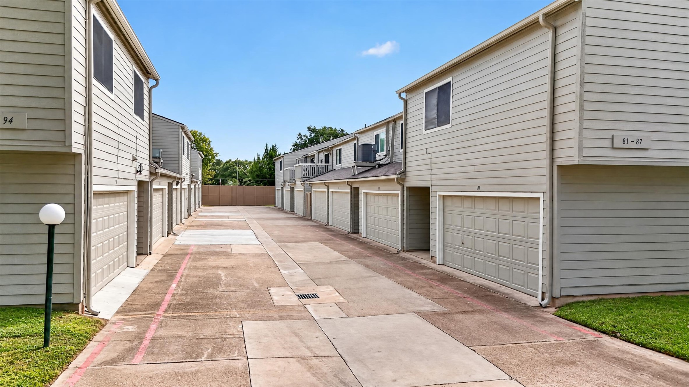 View down the rear garage alley, showing the attached two-car garages serving each townhome.