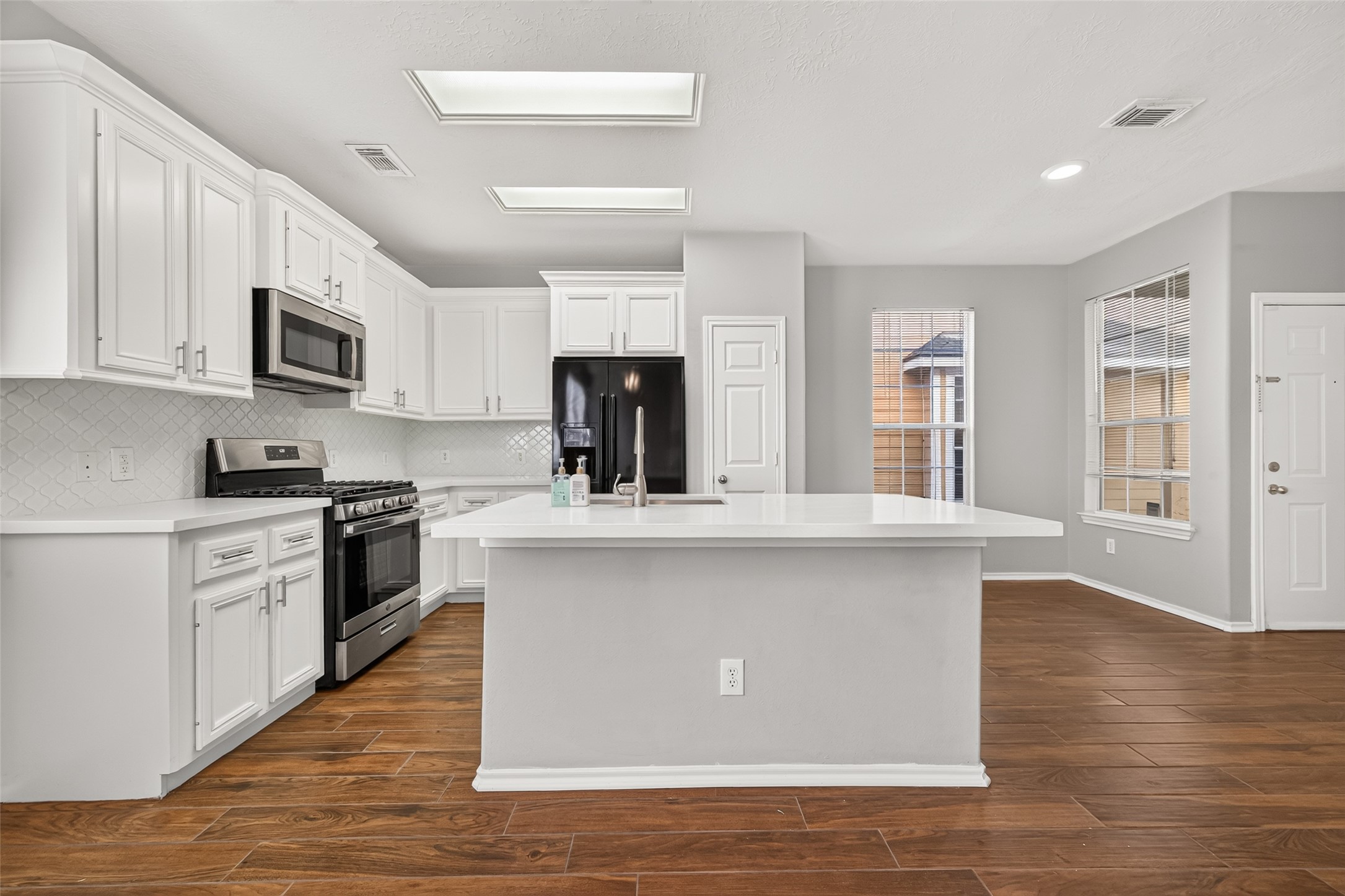 Completely renovated kitchen with white cabinets, beautiful backsplash and quartz countertops