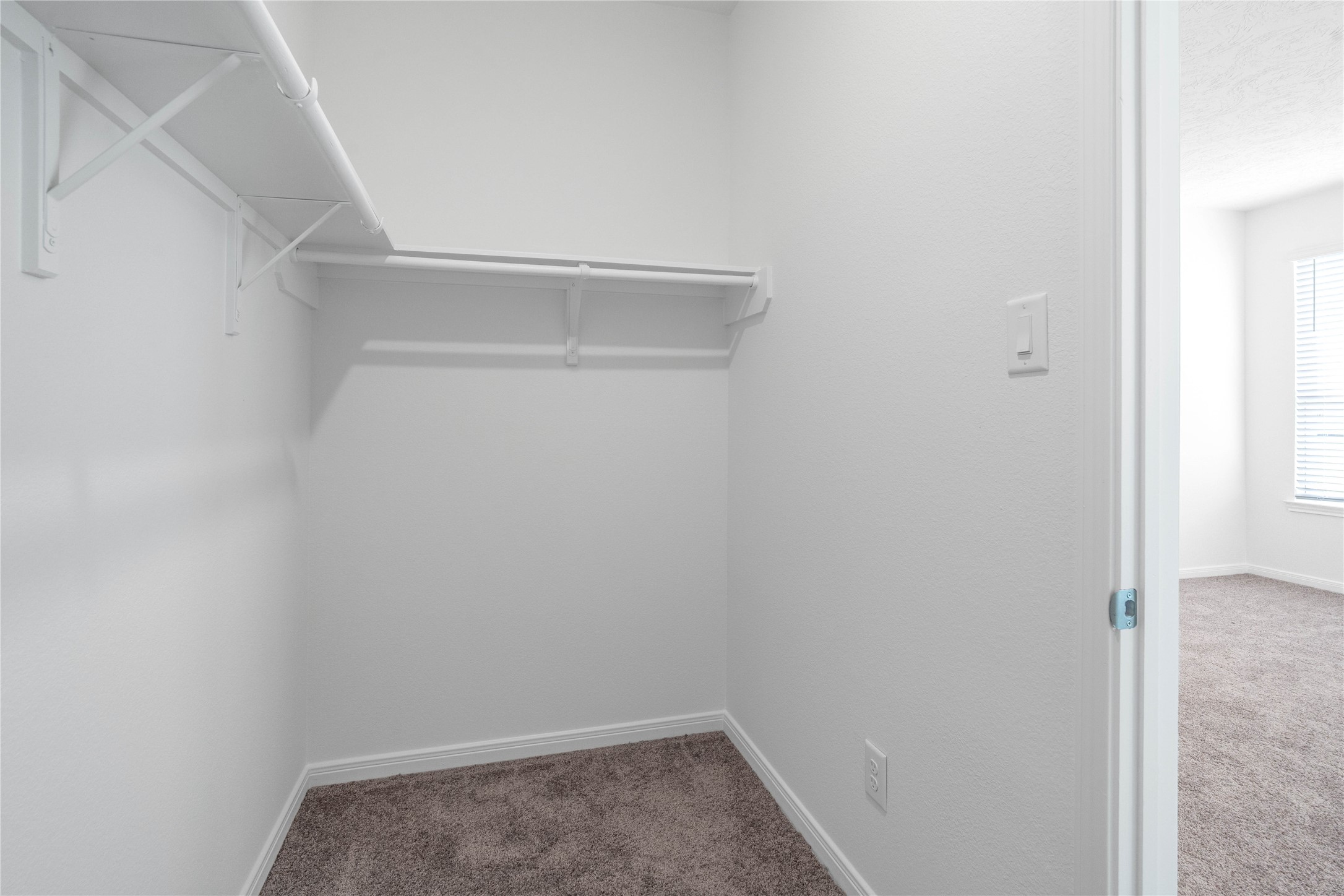 The spacious primary bedroom walk-in closet offers shelving, hanging rods, and ample storage space to keep your wardrobe organized.