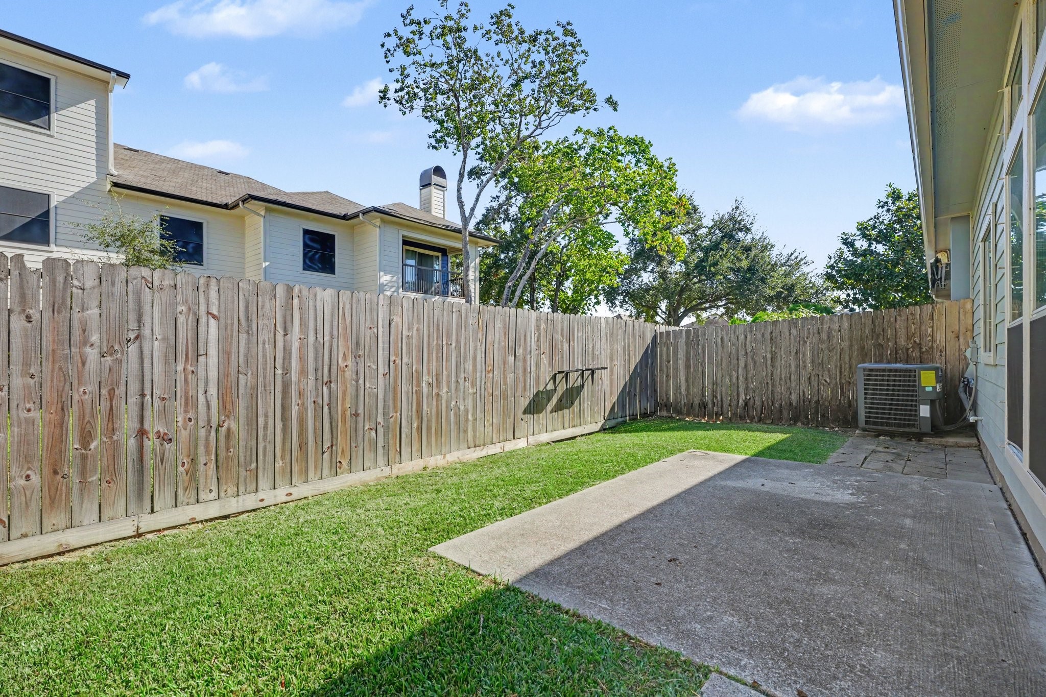 Fenced in backyard featuring a patio area and wraparound green space.