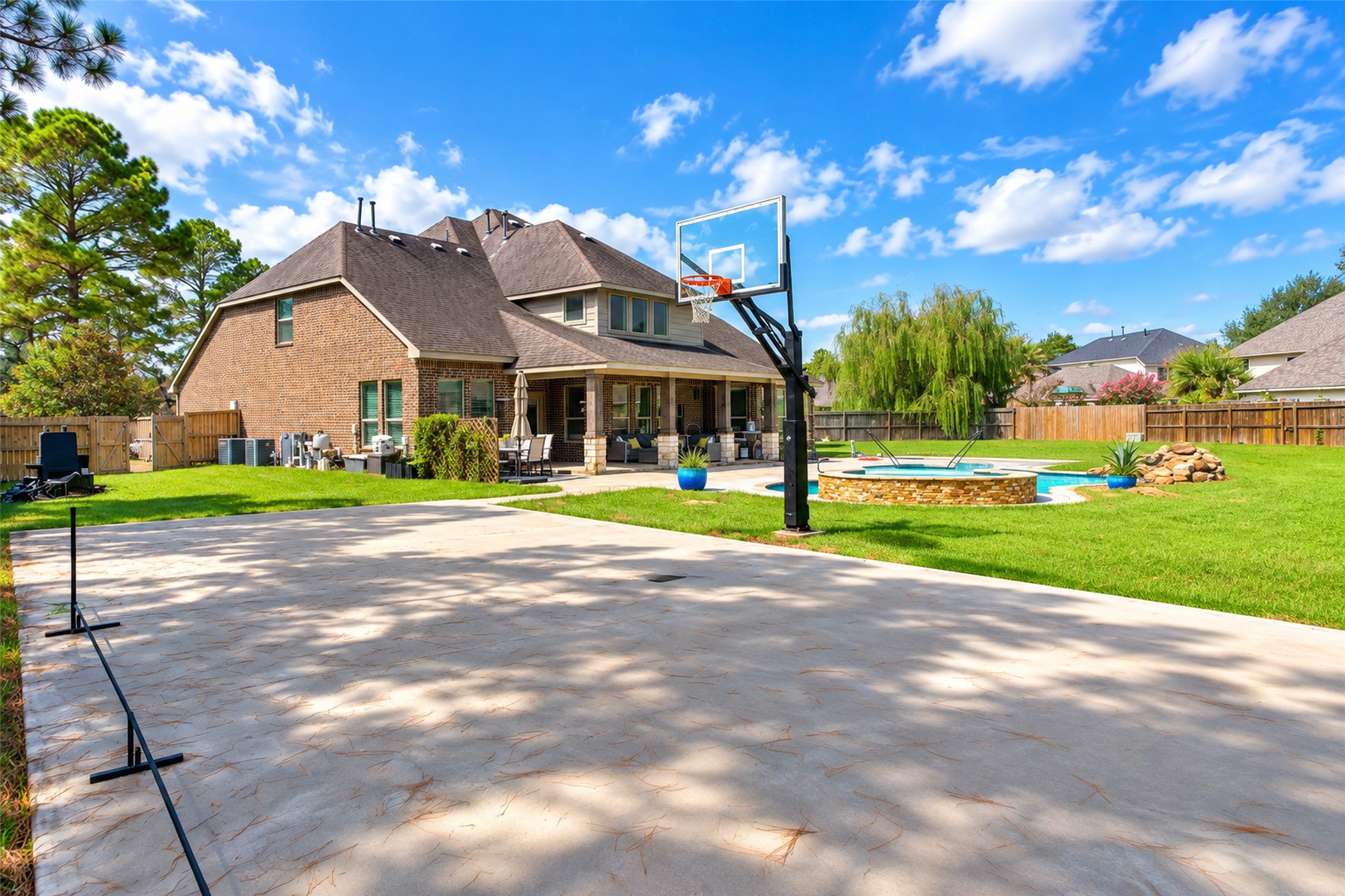 Sport court with basketball goal, pool beyond