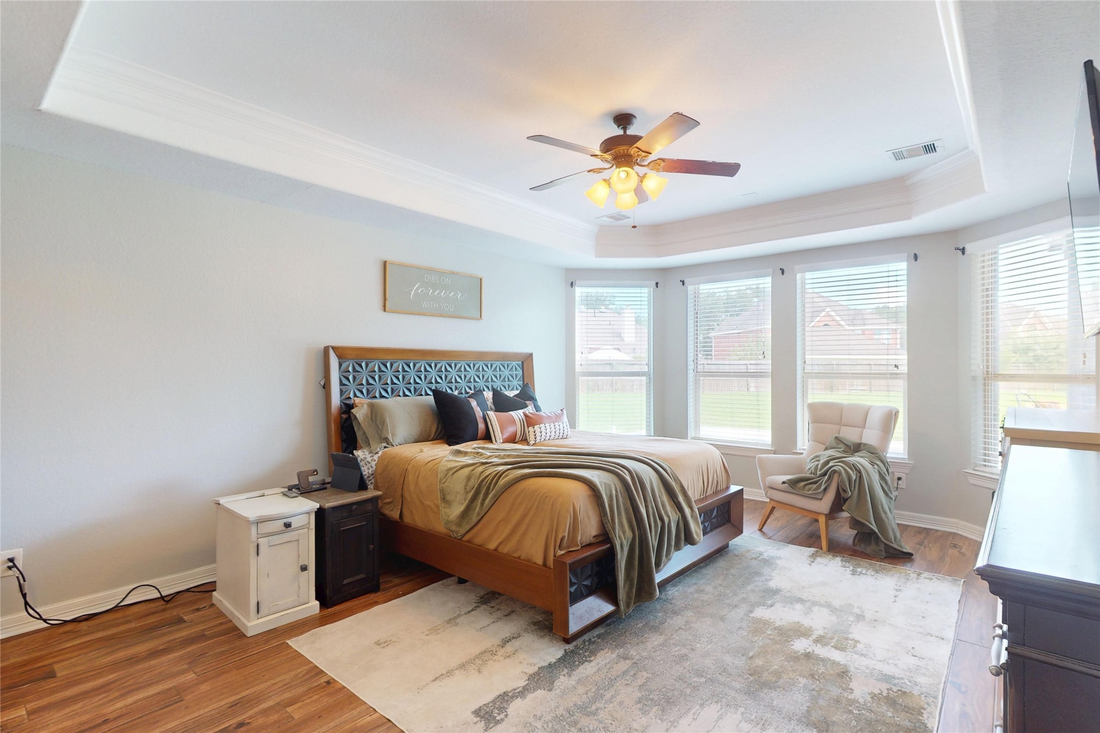 Primary bedroom with tray ceiling and a bank of windows