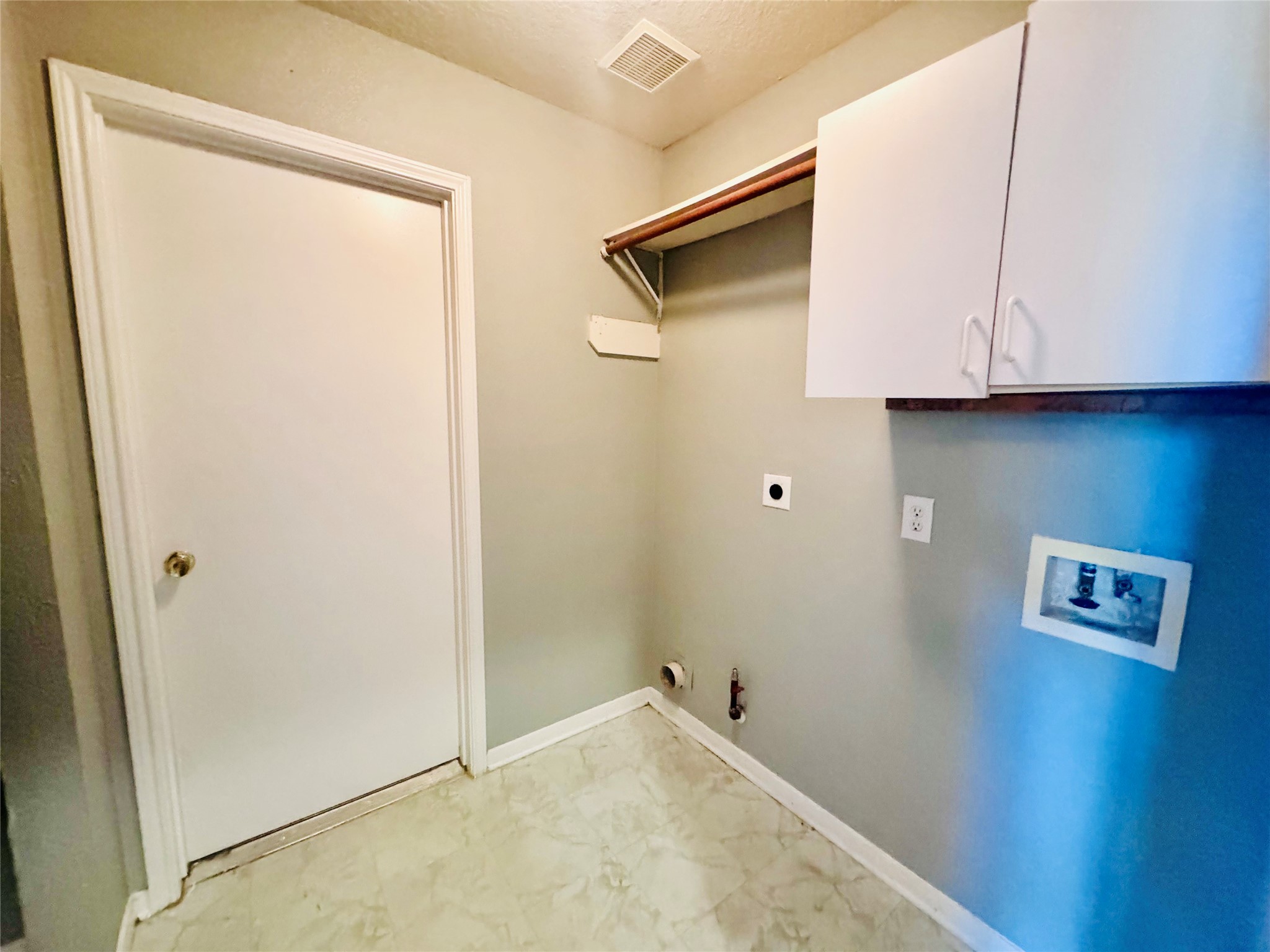 Spacious laundry room with ample storage, featuring upper cabinets.