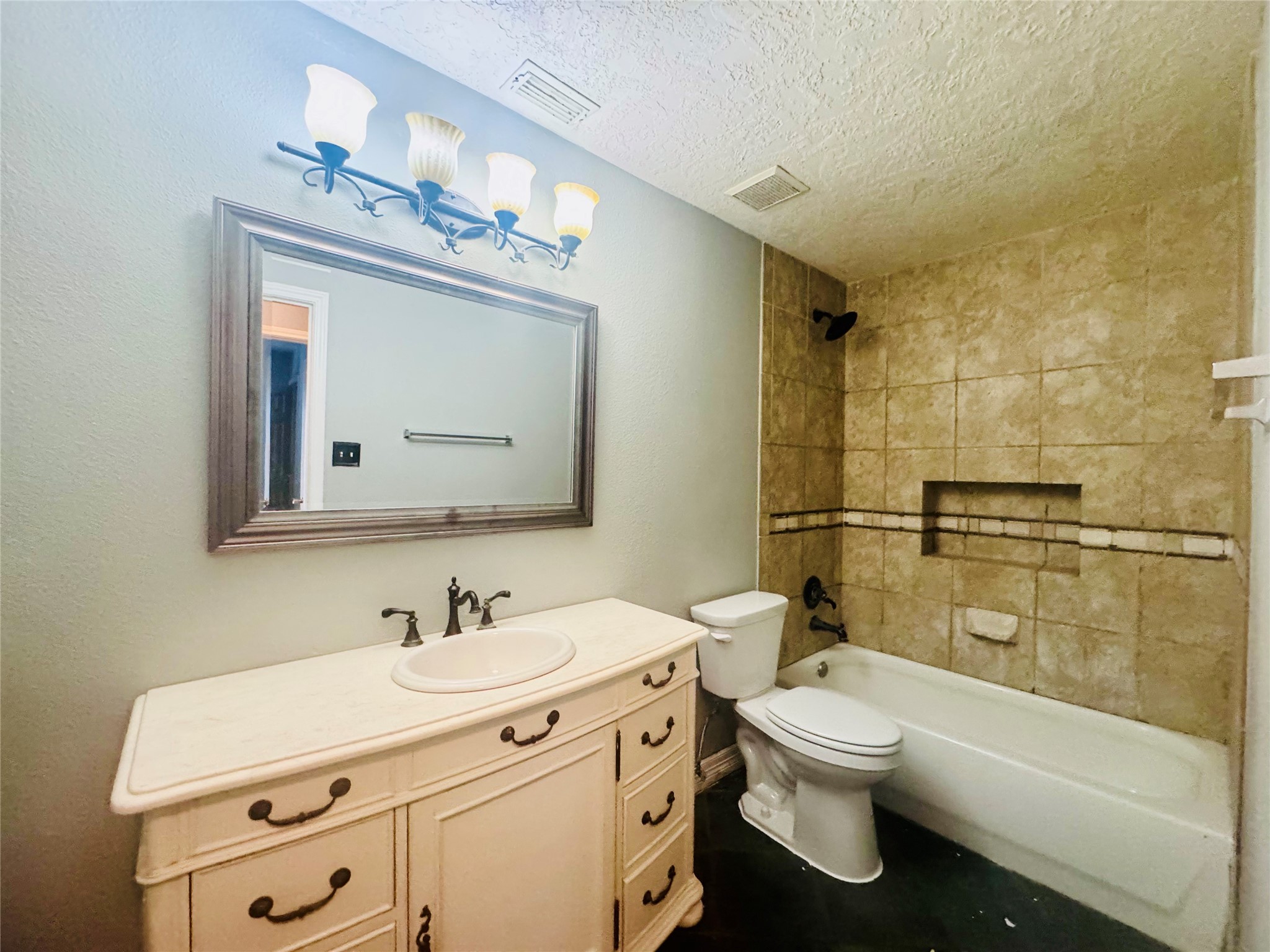 Charming bathroom featuring a classic vanity with ample storage, elegant light fixtures, and a tub-shower combo with stylish tile work.