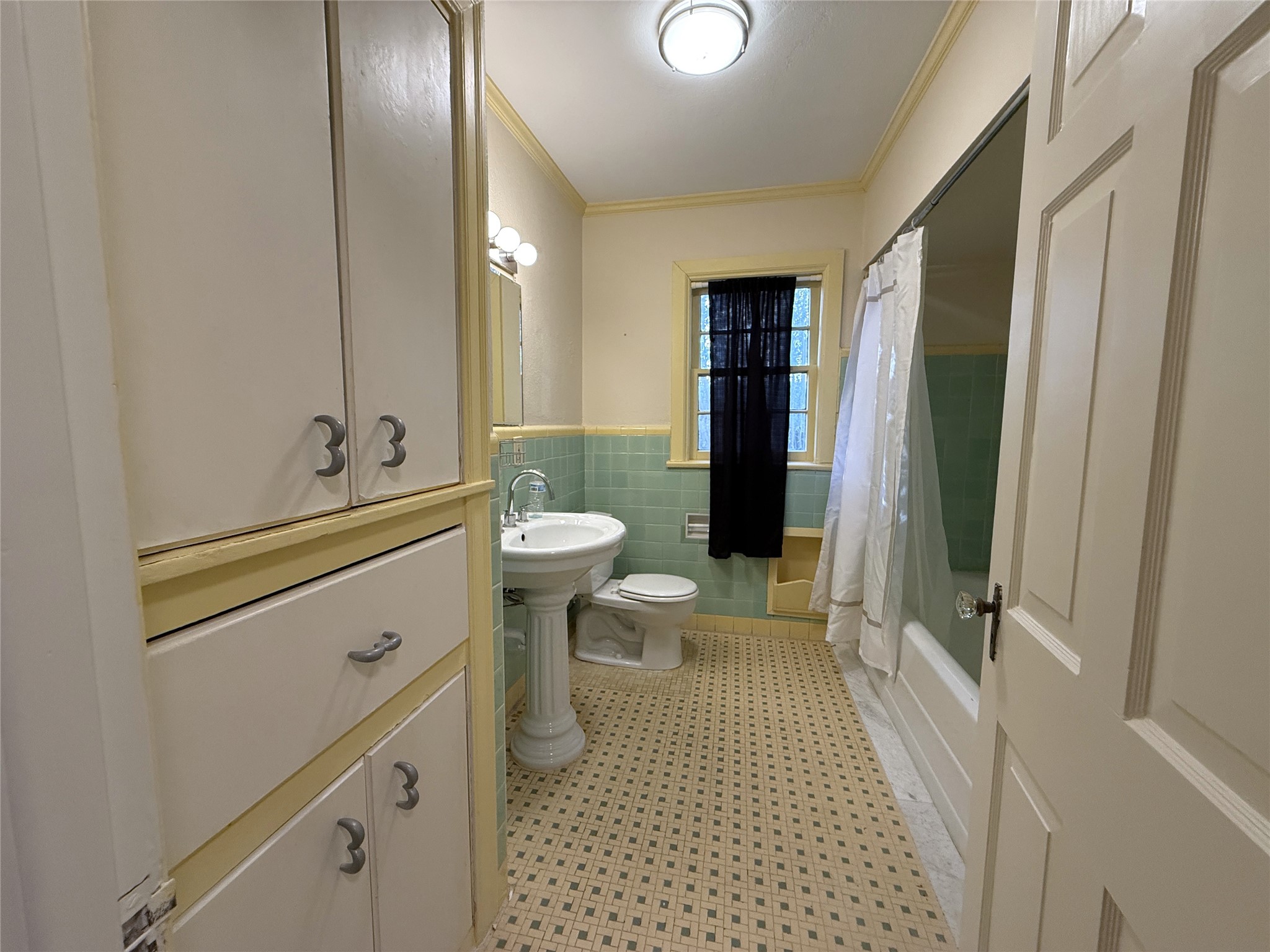 The hallway bath features vintage tile, tub/shower combo, linen storage & built-in hamper.