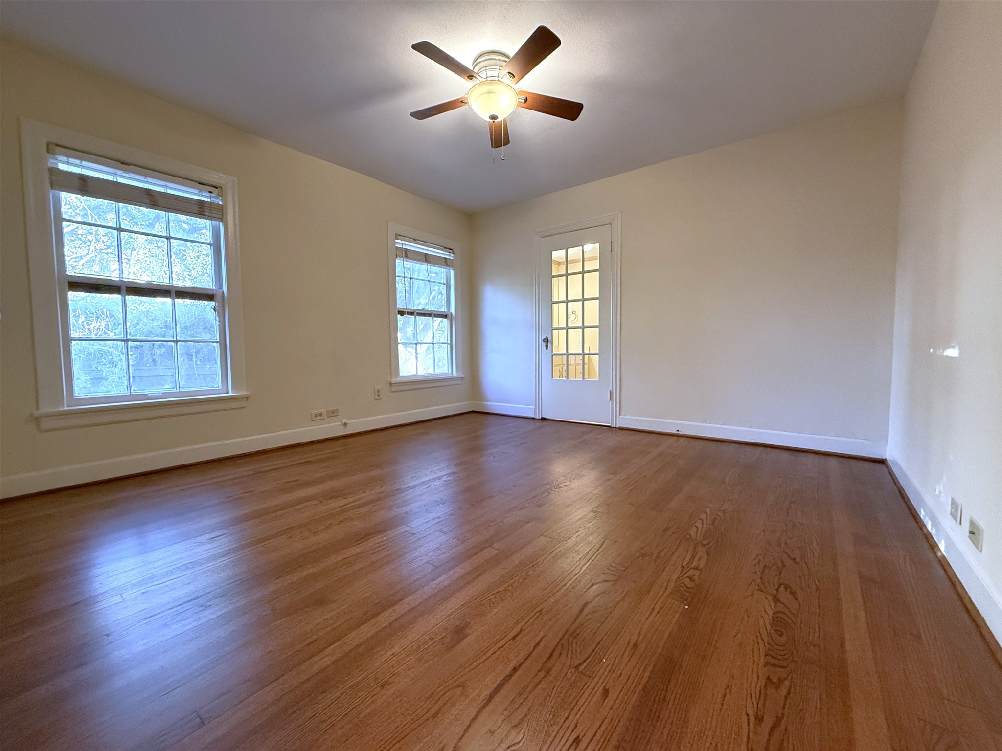 The primary bedroom with ceiling fan. Beyond the glass paned door is the primary bathroom.
