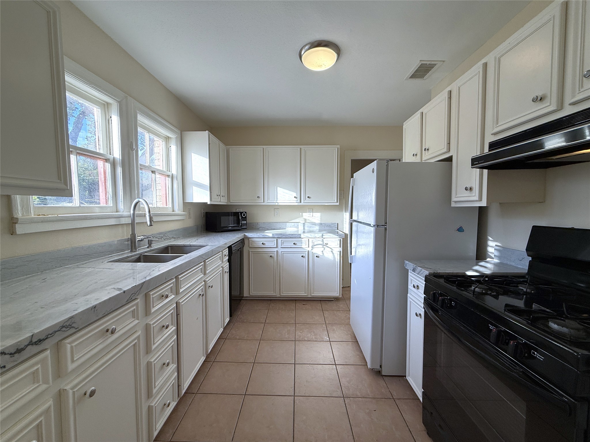 The spacious kitchen offers stone counter tops, dishwasher, gas cooking and lots of storage space. Natural light flows in from twin windows above the sink.