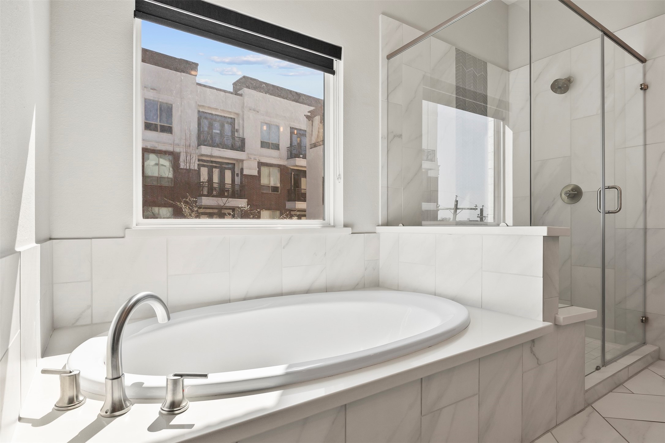 Primary bathroom featuring a soaking tub positioned beside large windows, creating a bright and relaxing retreat.