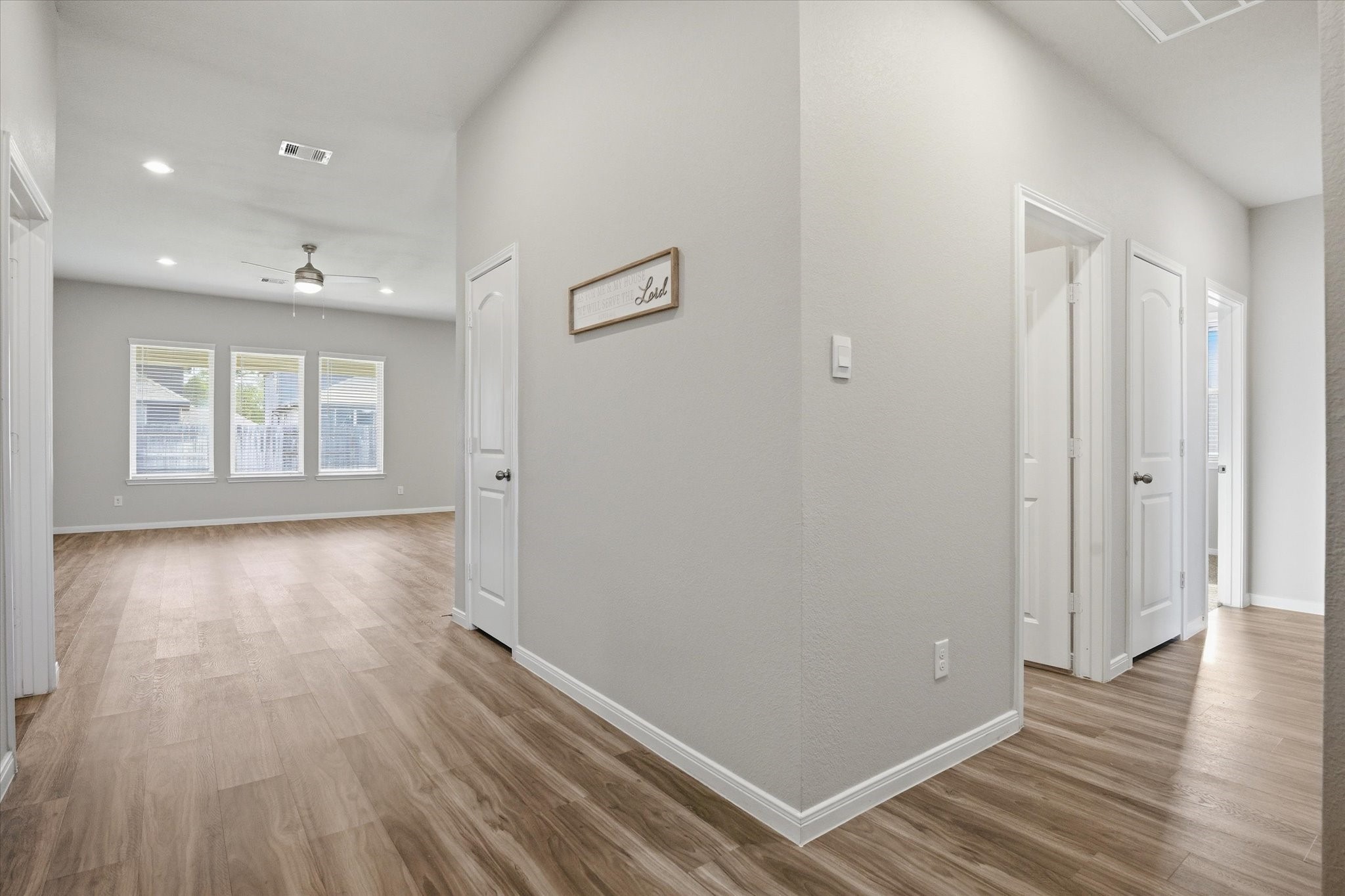 This photo shows a spacious, well-lit pantry with multiple white shelves, perfect for organized storage. The room has a clean, modern look with wood flooring.
