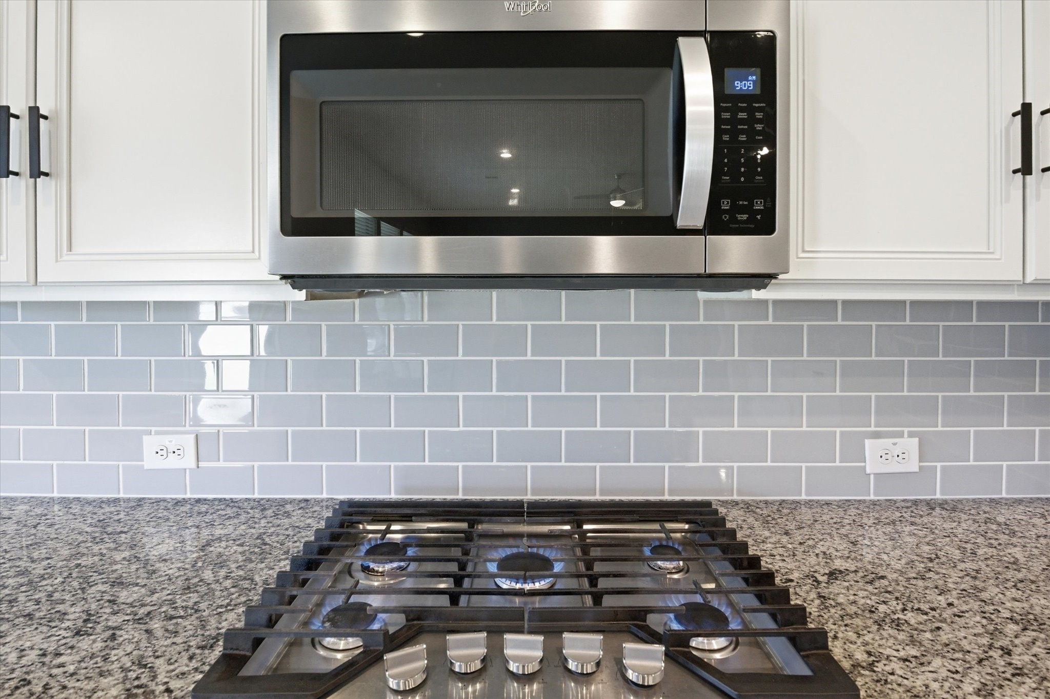This is a utility room with hookups for a washer and dryer. It features a shelf for storage, recessed lighting, and wood-style flooring, providing a functional and tidy space for laundry tasks.