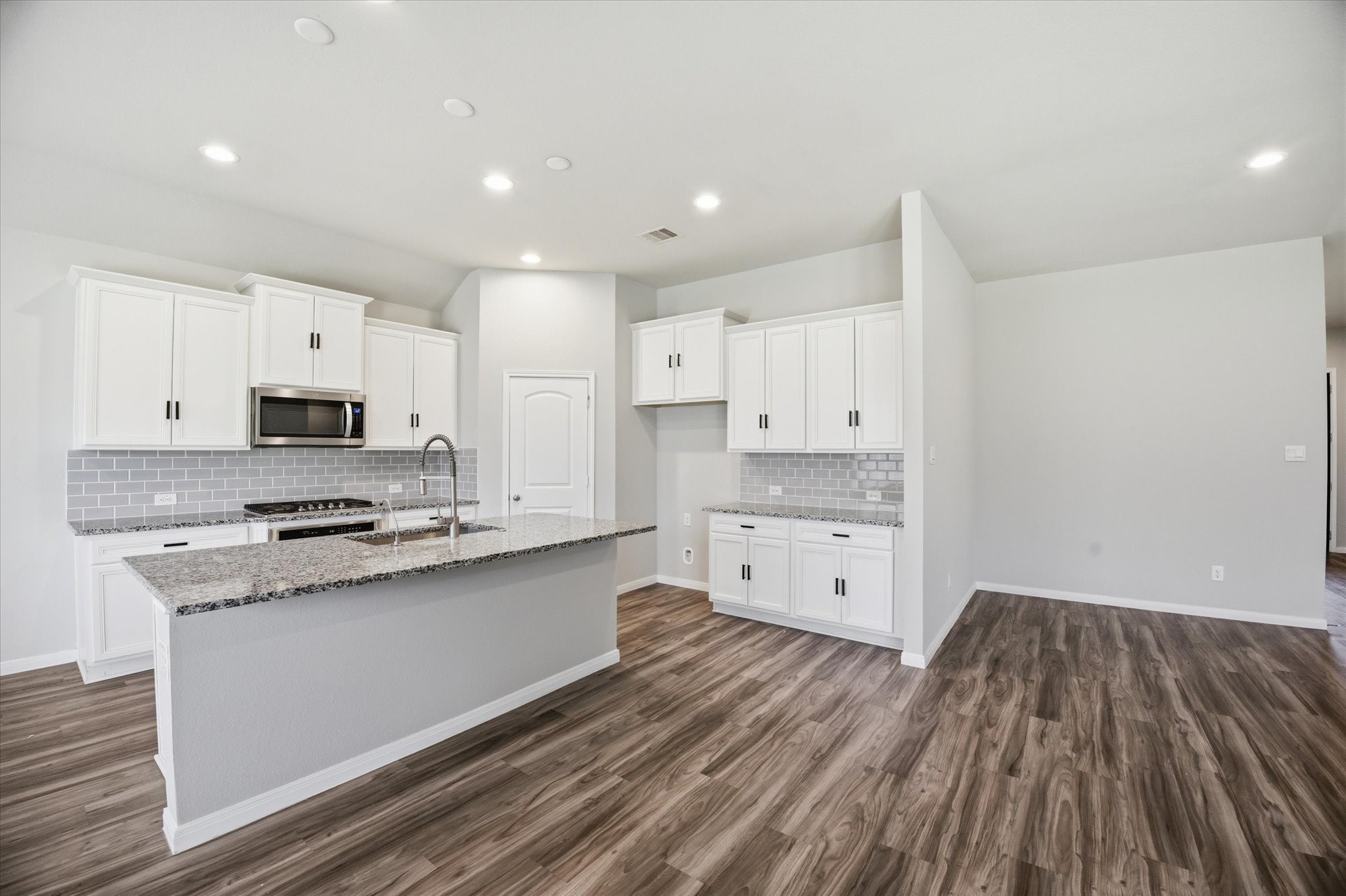 This is a spacious walk-in closet with neutral walls and carpeted flooring, featuring ample shelving and hanging space for storage.