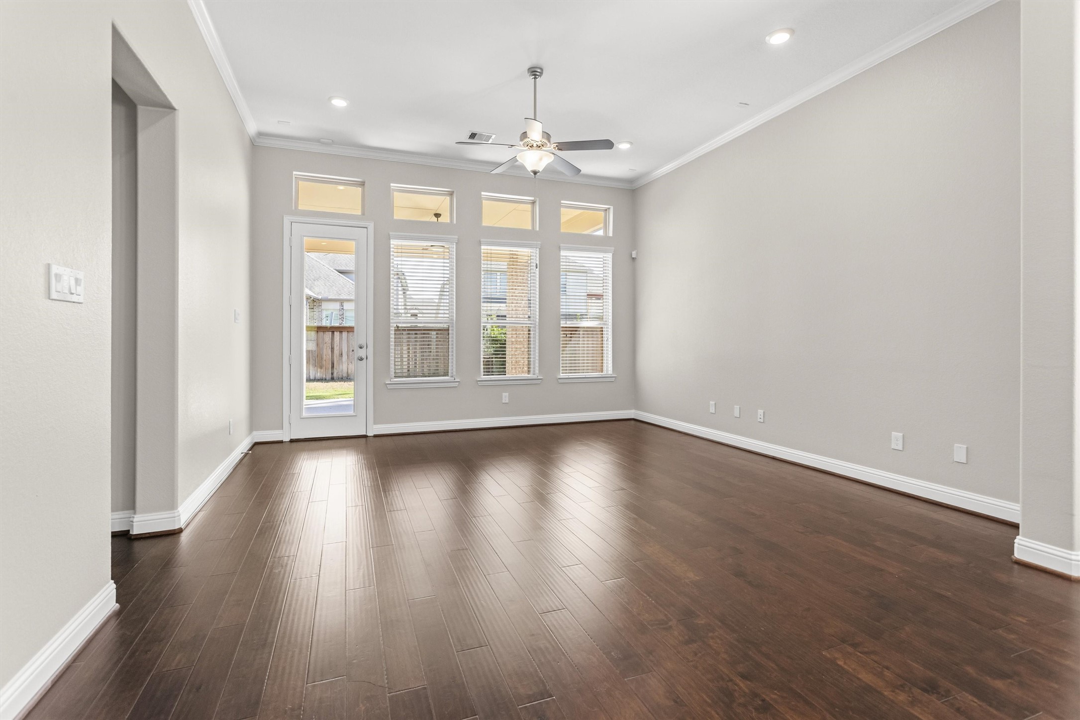 Living area with recessed lighting in addition to a central light. Glass door to the covered back patio.