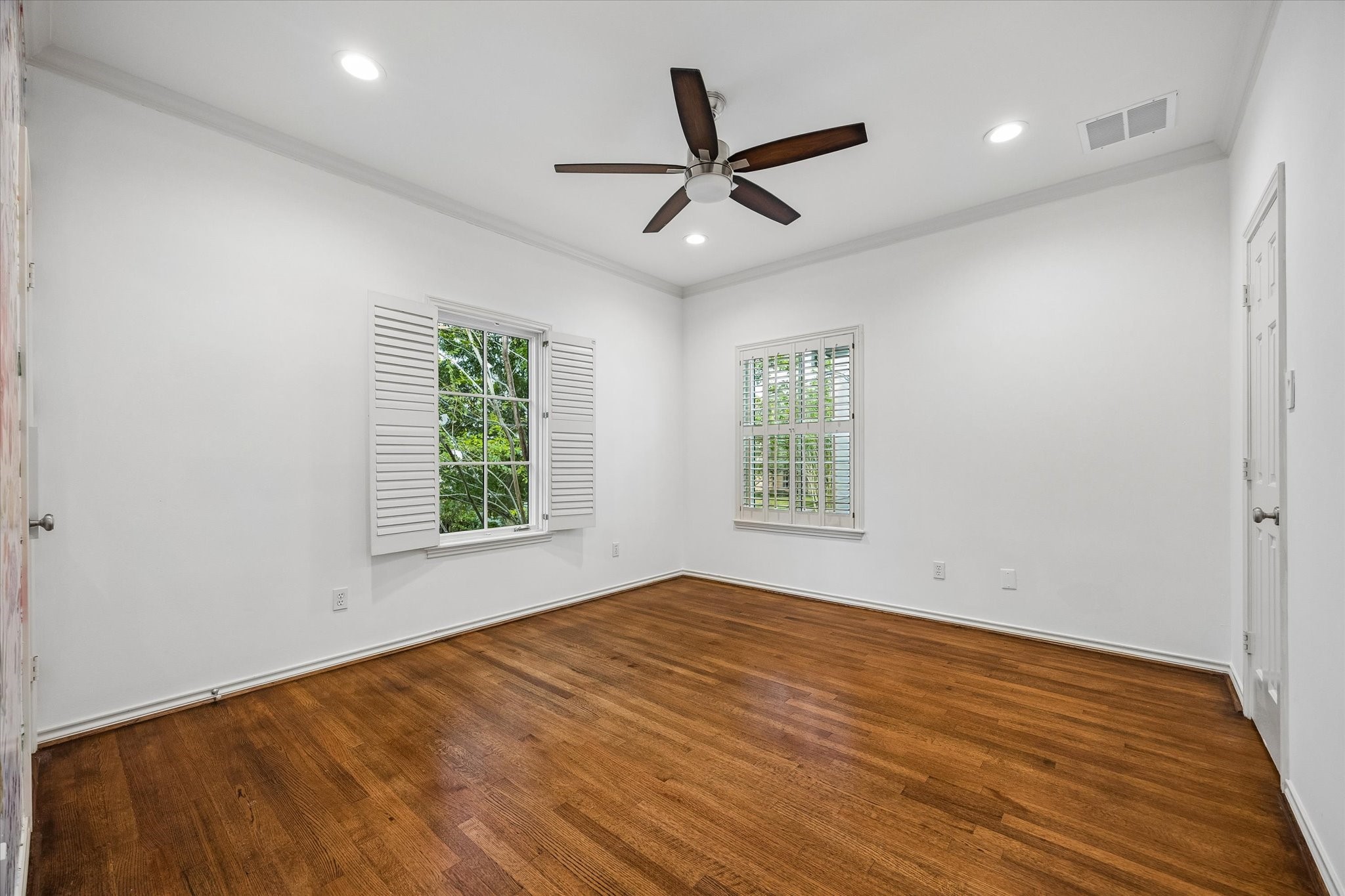 Secondary bedroom with hardwoods, shutters, and 2026 paint.