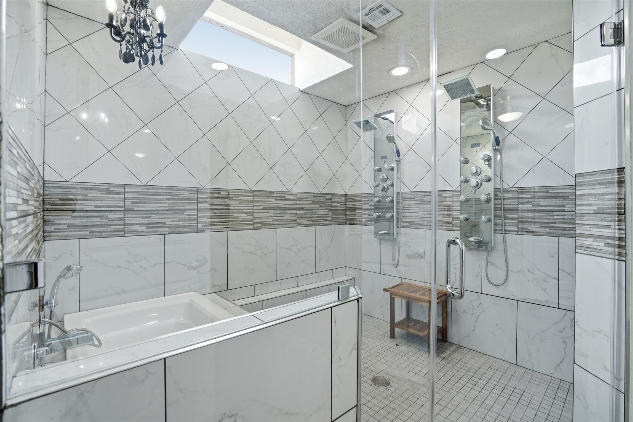 Primary bath features a glass enclosed shower with dual rainfall showerheads, soaking tub, skylight, and elegant finishes throughout.