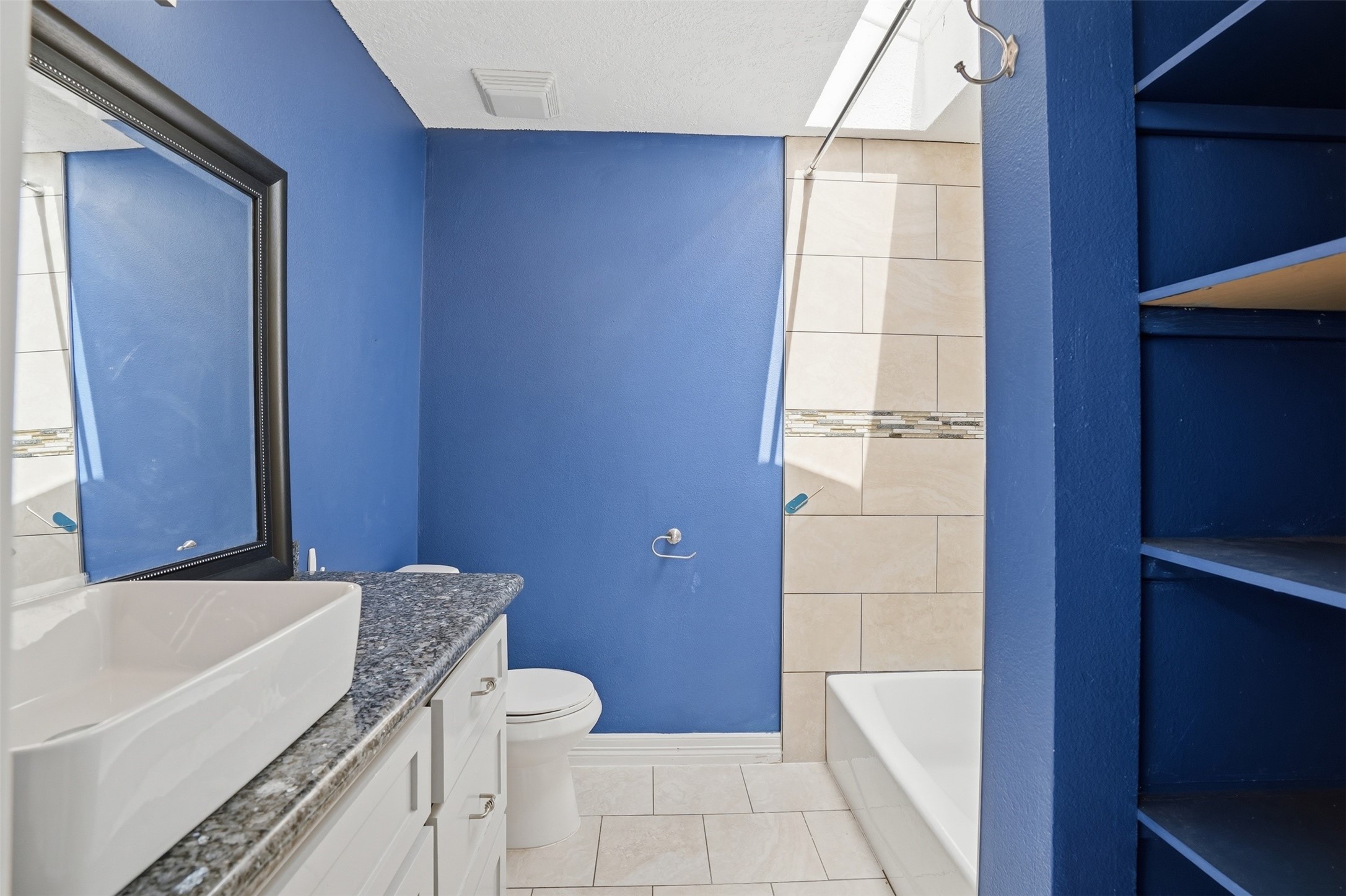 Bright bathroom located off the secondary bedroom, featuring a modern vanity with sink and granite countertop.
