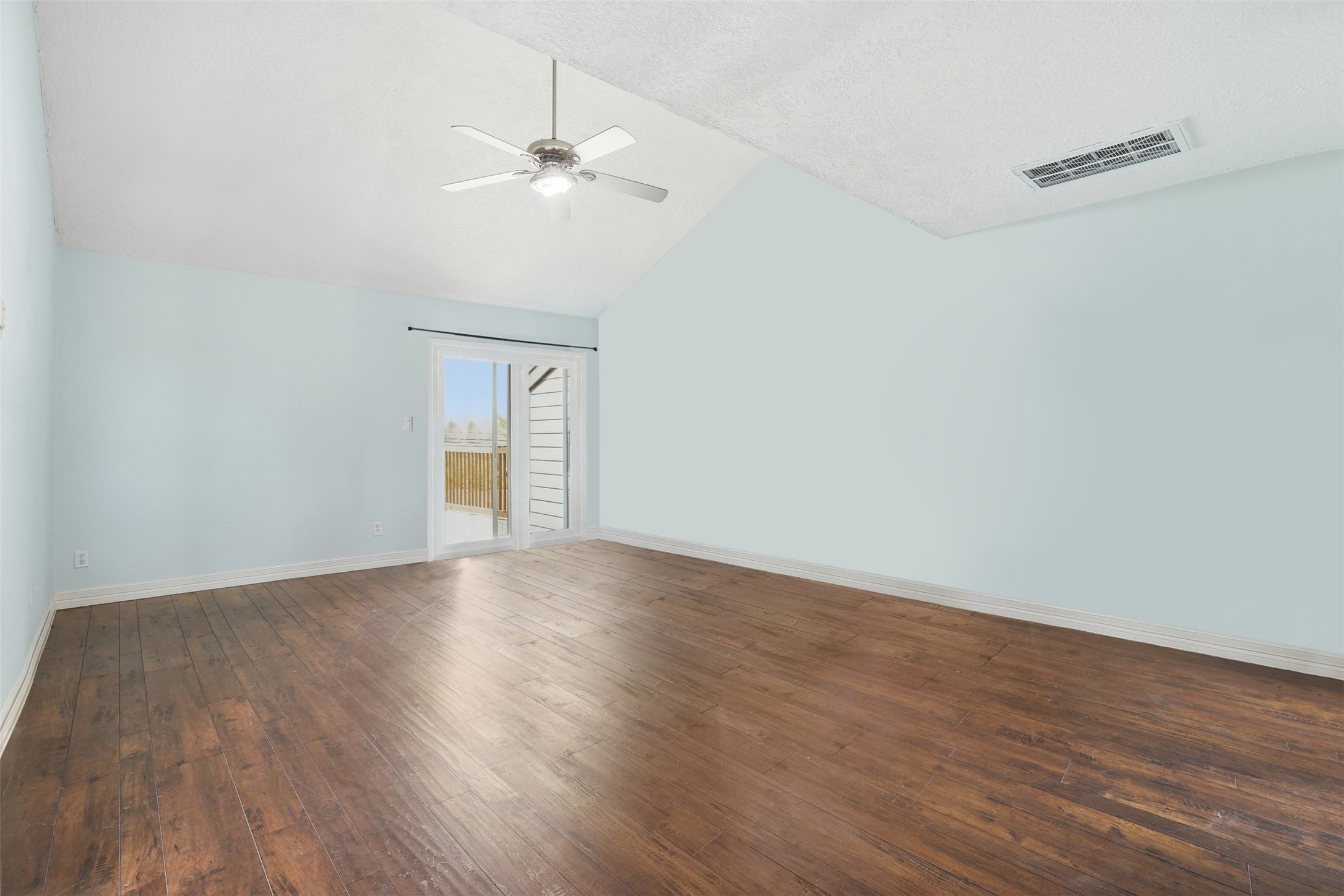 Spacious primary suite featuring high ceilings and abundant natural light, with sliding glass doors leading to a private outdoor space.
