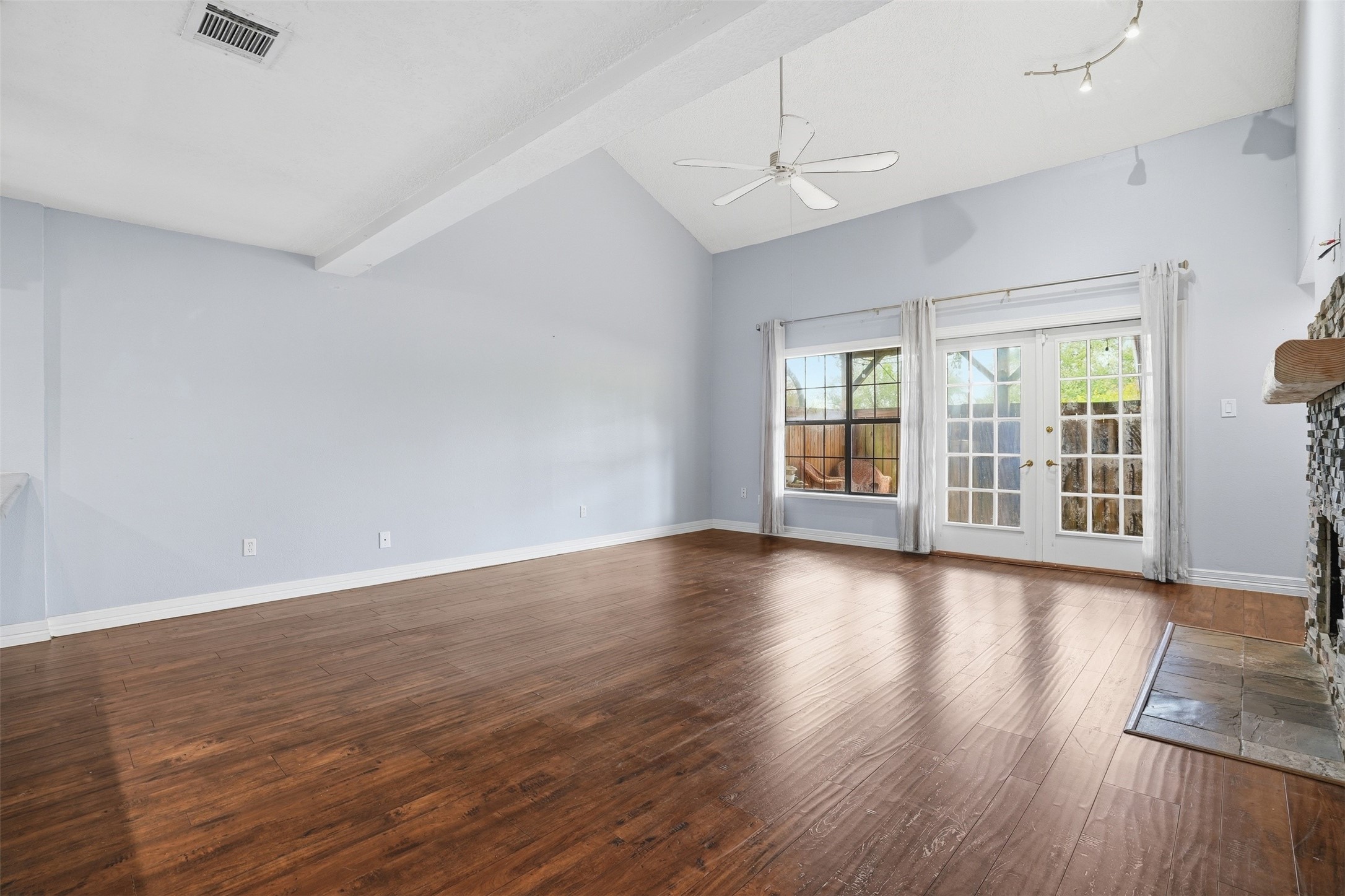 Spacious living room featuring soaring ceilings, wood flooring, and abundant natural light from large windows and French doors leading to the backyard. Spacious living room featuring soaring ceilings, wood flooring, and abundant natural light from large windows and French doors leading to the backyard.