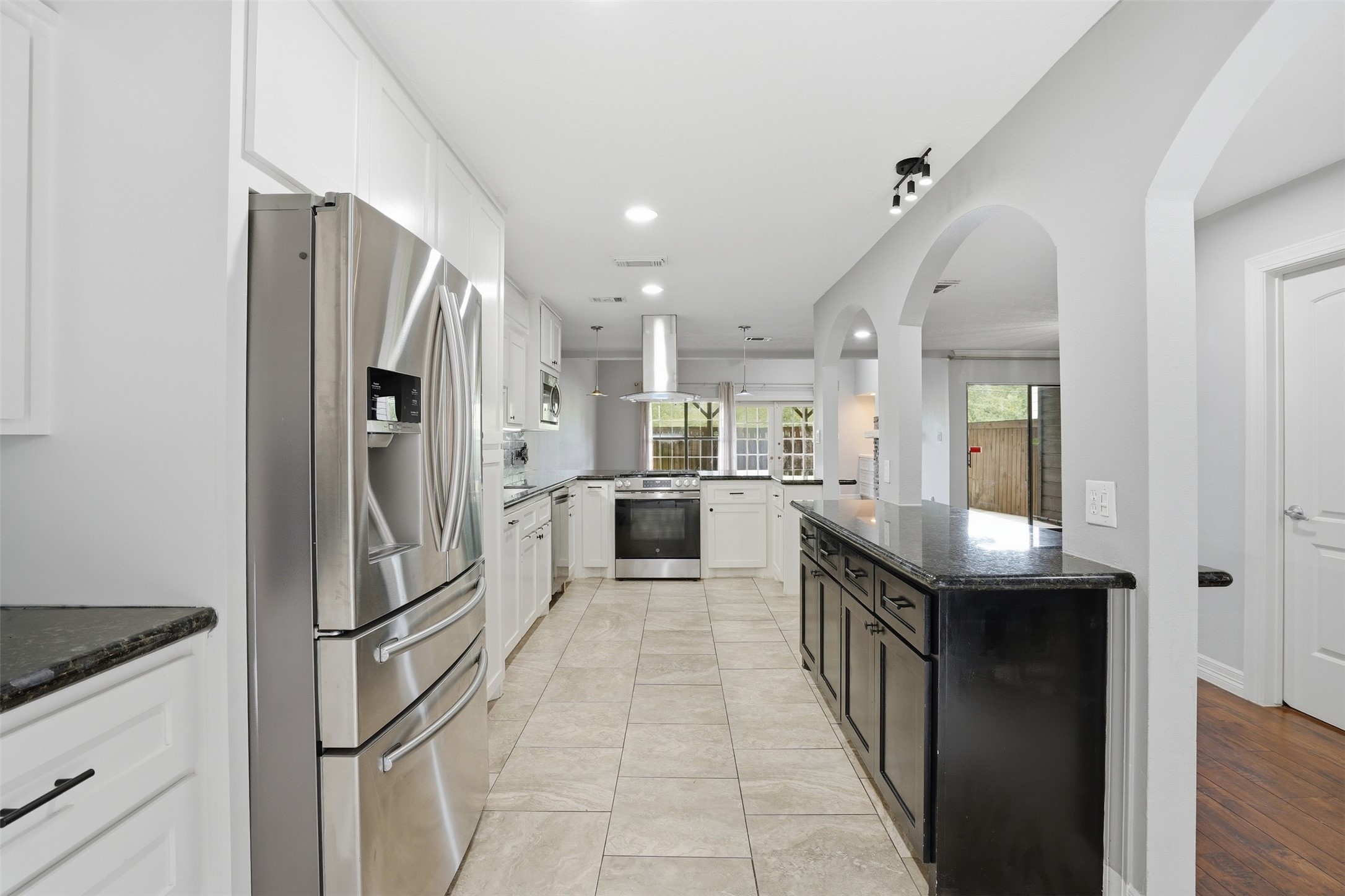 Bright, modern kitchen with granite countertops and ample cabinetry. Arched entryways and an open design create a seamless connection to the spacious living area.