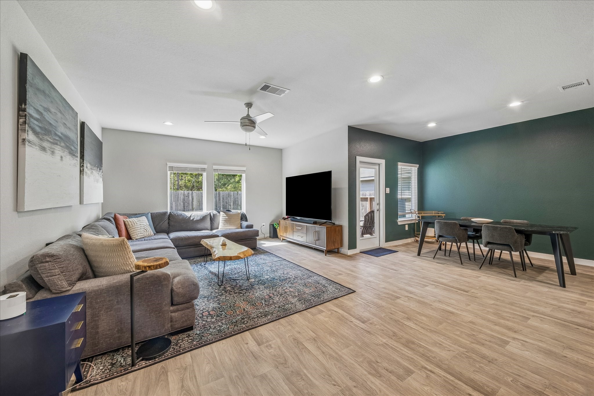 The calming green accent wall coordinates with the lush green backdrop of trees behind the property.