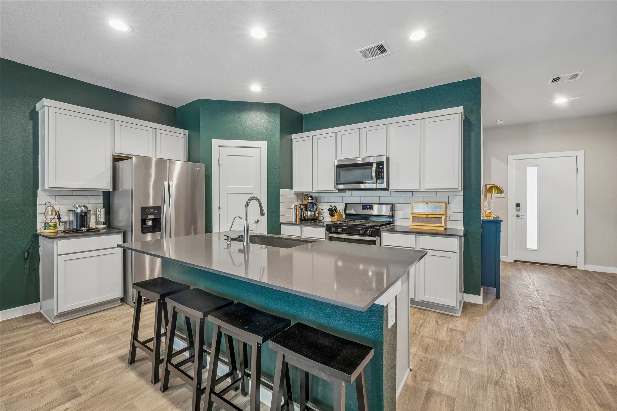 This open inviting plan offers a sleek modern kitchen with stainless steel appliances (refrigerator does not convey), walk in pantry and gleaming countertops.