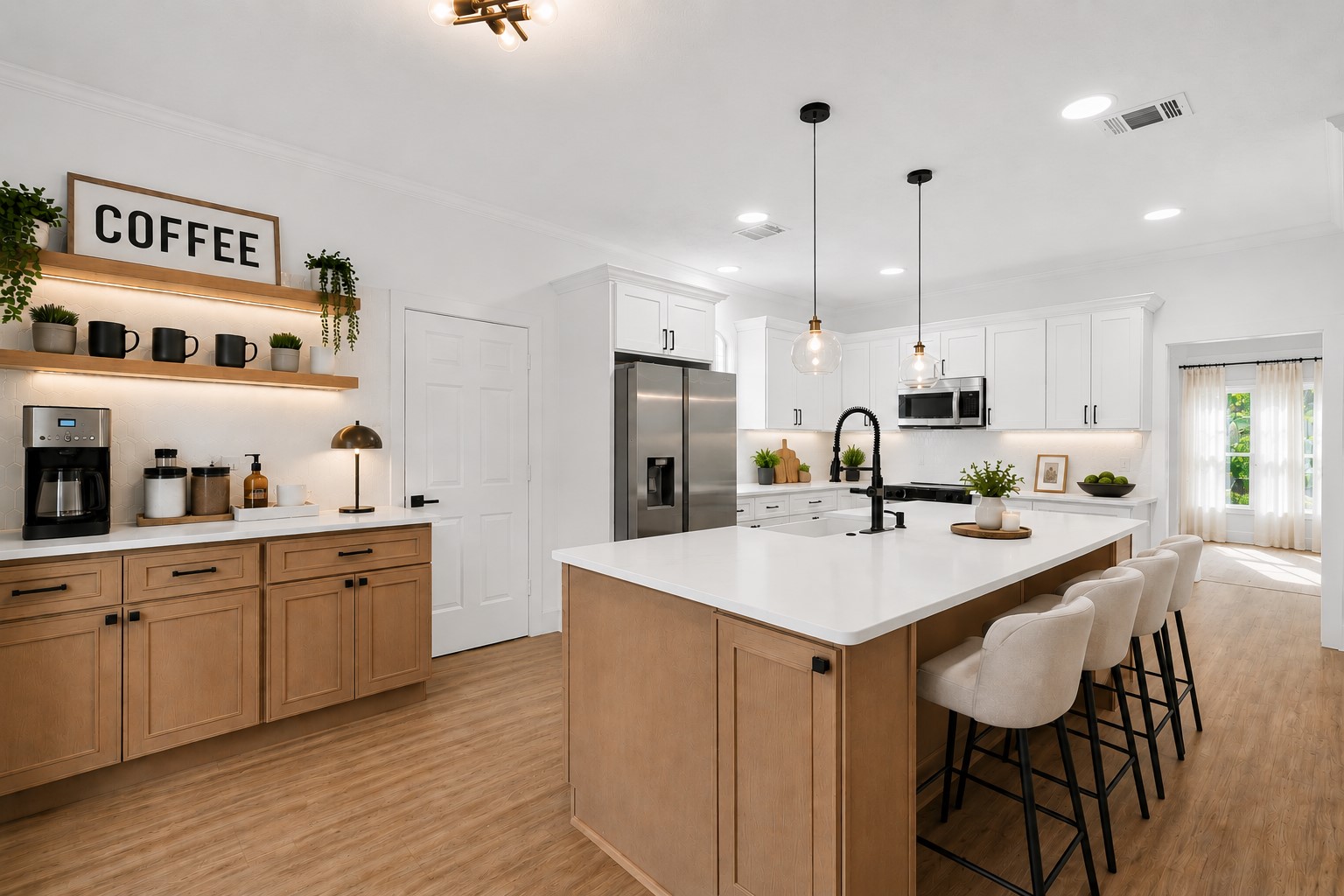Stylish kitchen featuring a spacious island with seating, modern pendant lighting, and ample cabinetry in a warm wood color, complemented by sleek stainless steel appliances and a cozy coffee nook. Photo digitally staged.