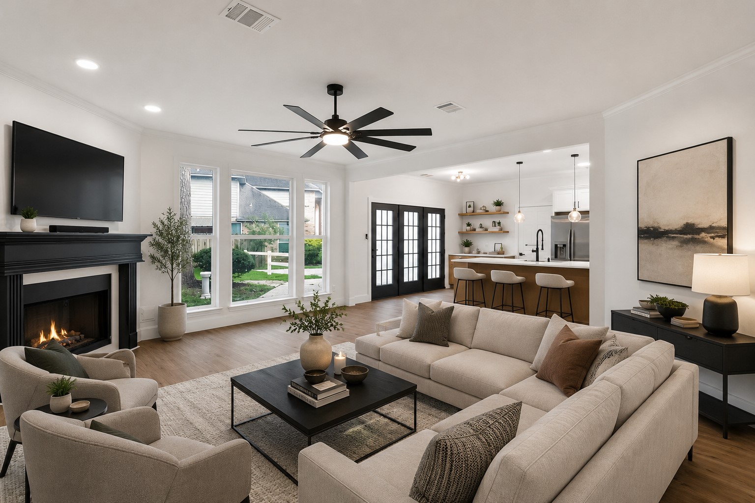 Spacious and inviting living area featuring a cozy fireplace, elegant ceiling fan, and large windows offering abundant natural light, seamlessly connected to a modern open kitchen with sleek countertops and stylish bar seating. Photo digitally staged.