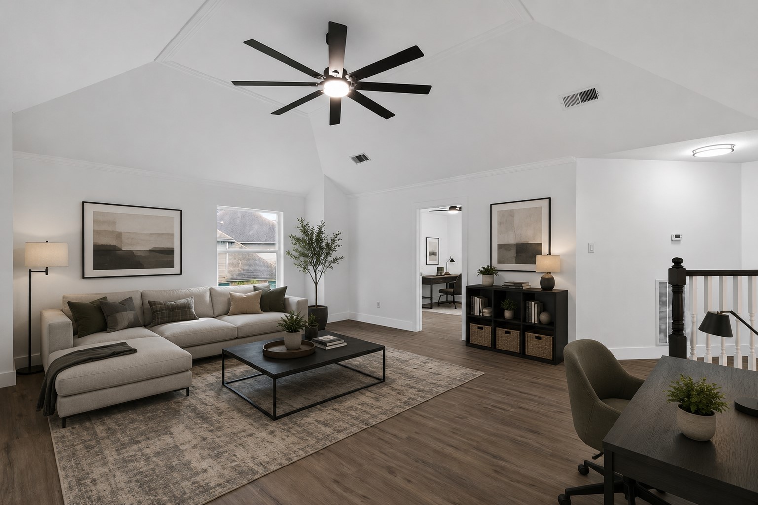 Spacious living area on second floor with vaulted ceilings, modern ceiling fan, and abundant natural light. Ready to create a perfect blend of comfort and functionality. Photo digitally staged.