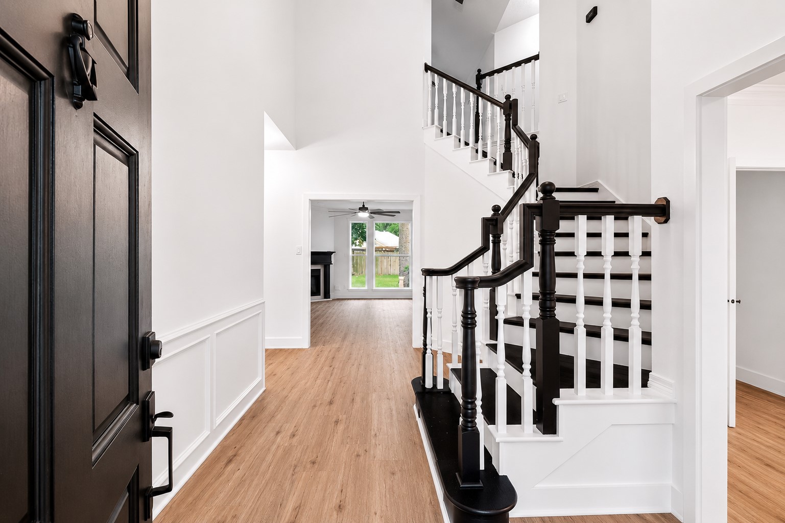 Elegant entryway featuring a striking staircase with dark wood accents and bright, airy interiors leading to a spacious living area.