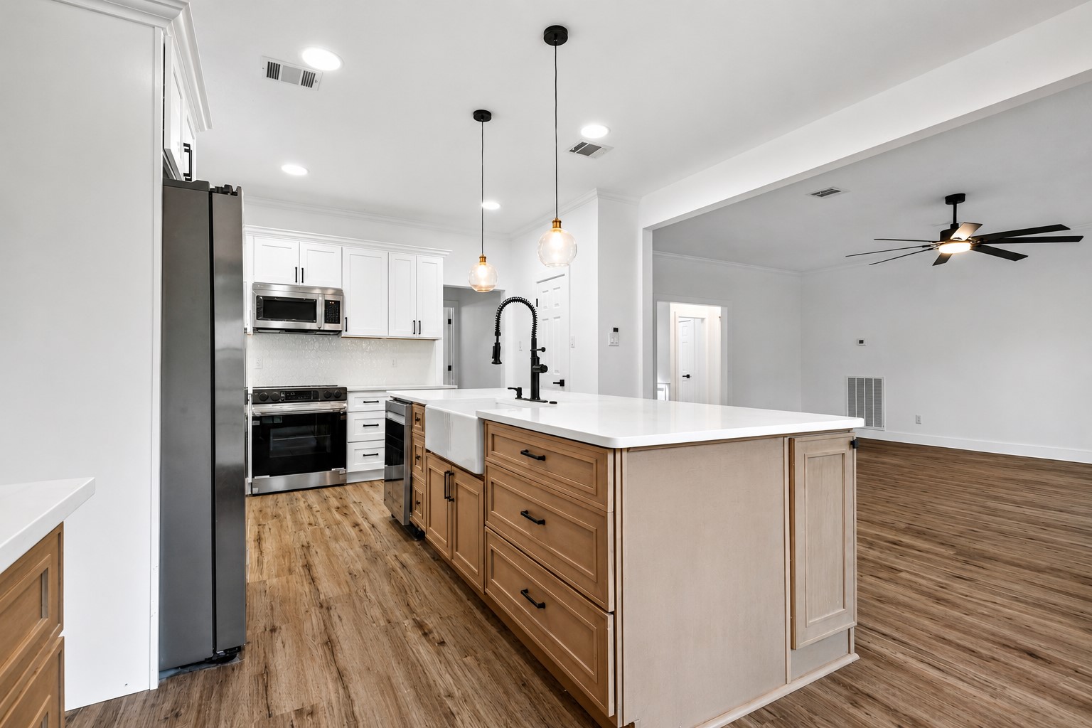 Modern kitchen with a spacious open layout, featuring sleek stainless steel appliances, elegant pendant lighting, and a large island with ample storage and counter space.