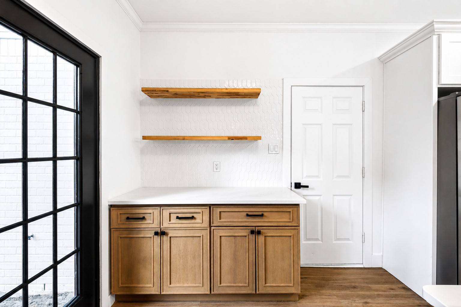 Charming kitchen nook featuring sleek wooden cabinets, open shelving, and a stylish white backsplash.