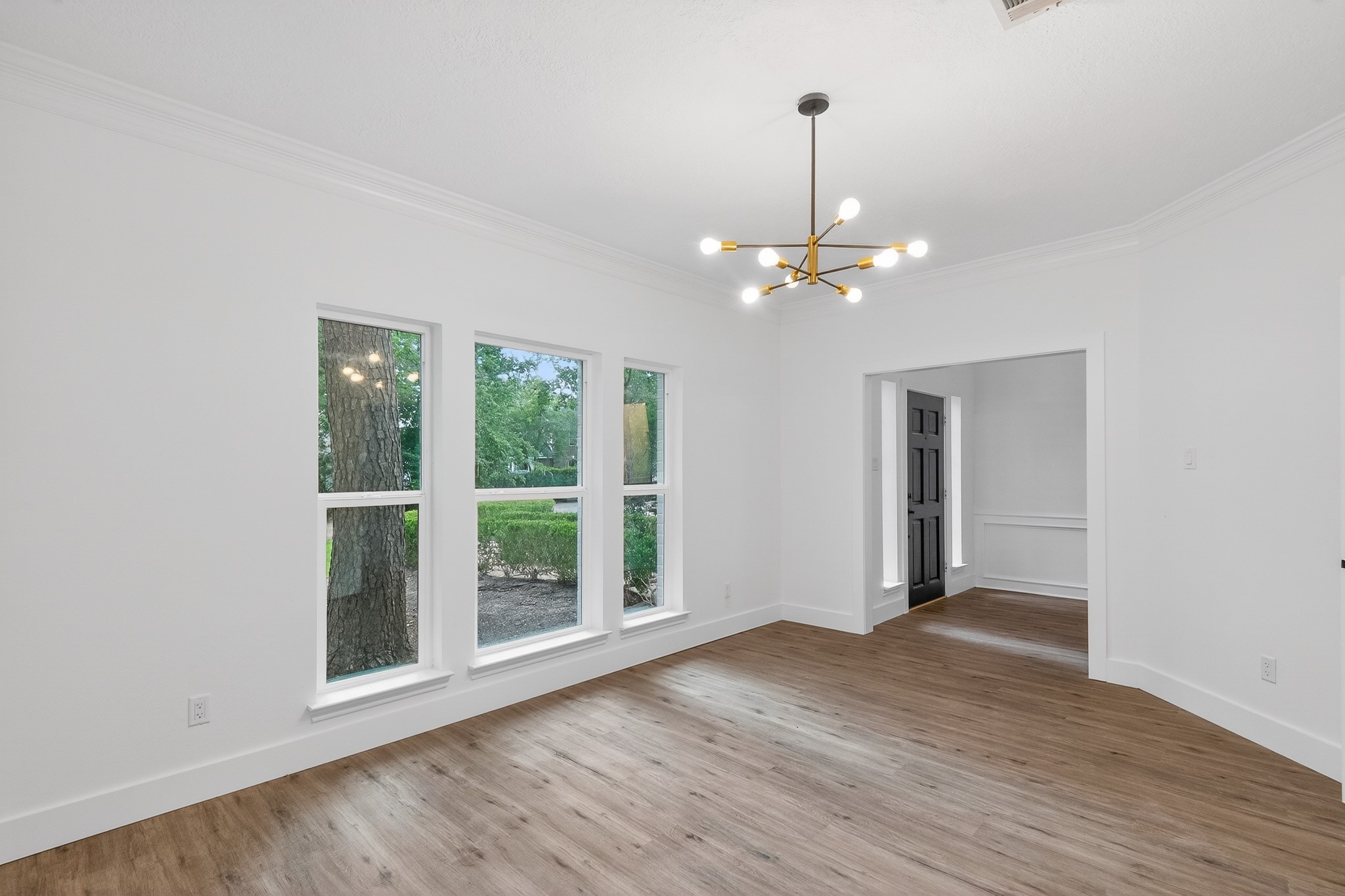 Bright dining area featuring large windows, modern chandelier, and elegant vinyl flooring.